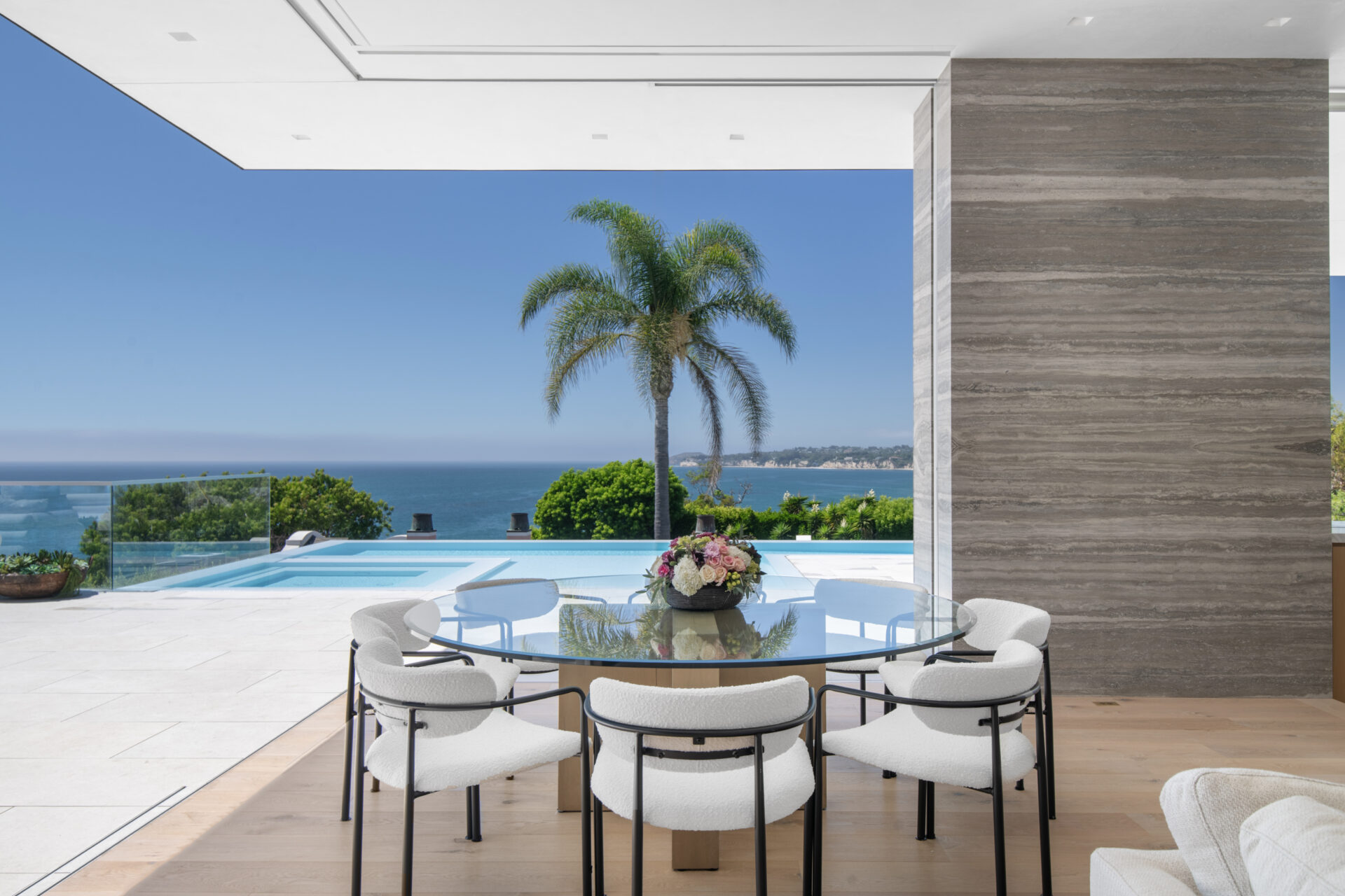 At the far corner of the great room, the dining area sits right along the disappearing glass wall, giving it a direct connection to the terrace.
