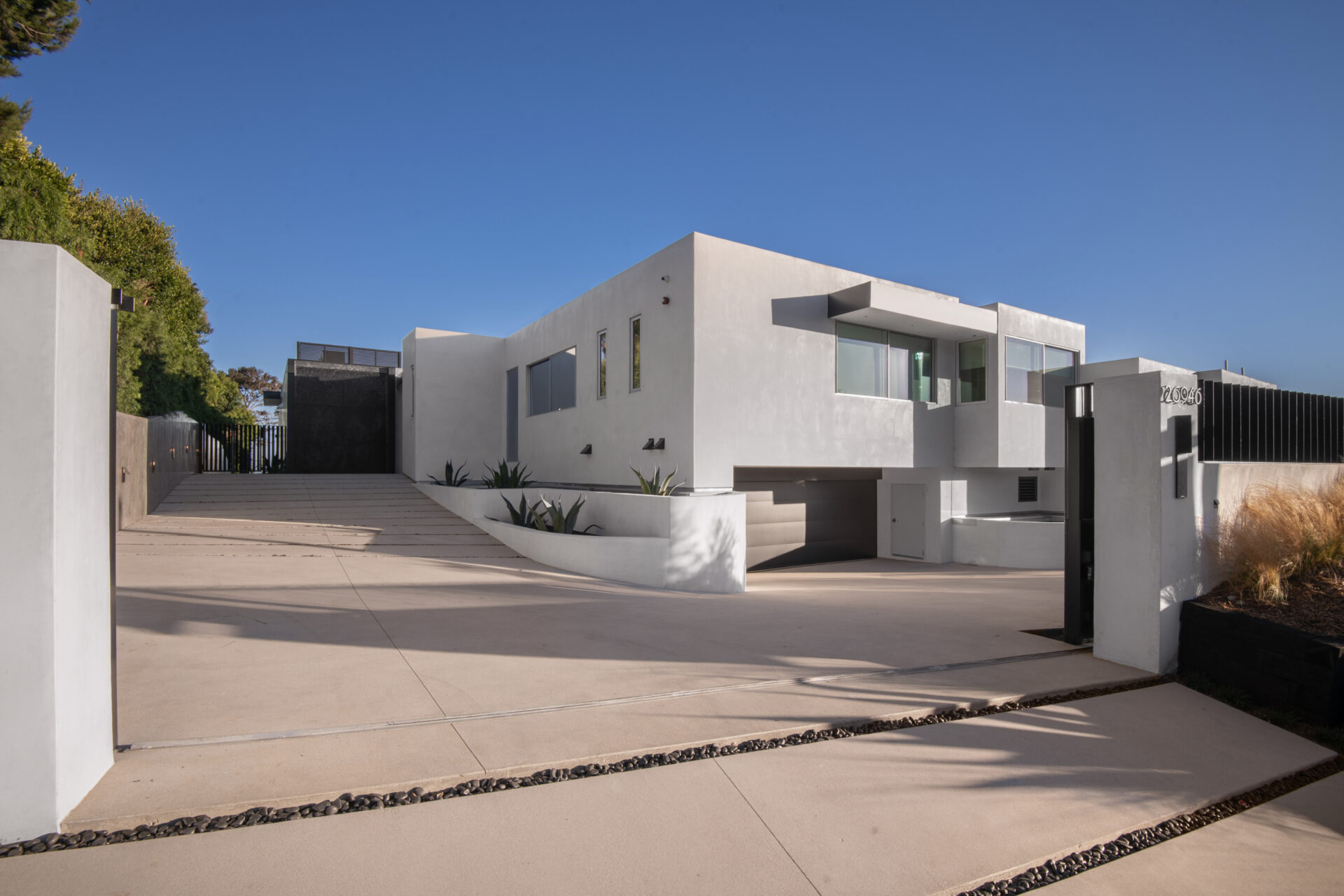 The entry to Hunter Pence’s Malibu property begins with a long, sloped concrete driveway that leads to a clean-lined white exterior.