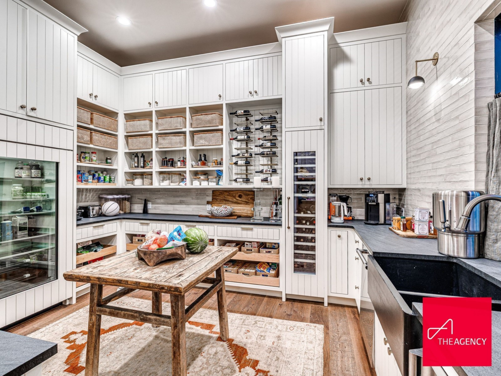 Just beyond the main kitchen, a spacious butler’s pantry features floor-to-ceiling cabinetry, open cubbies, wine storage, a beverage refrigerator, and additional counter space.