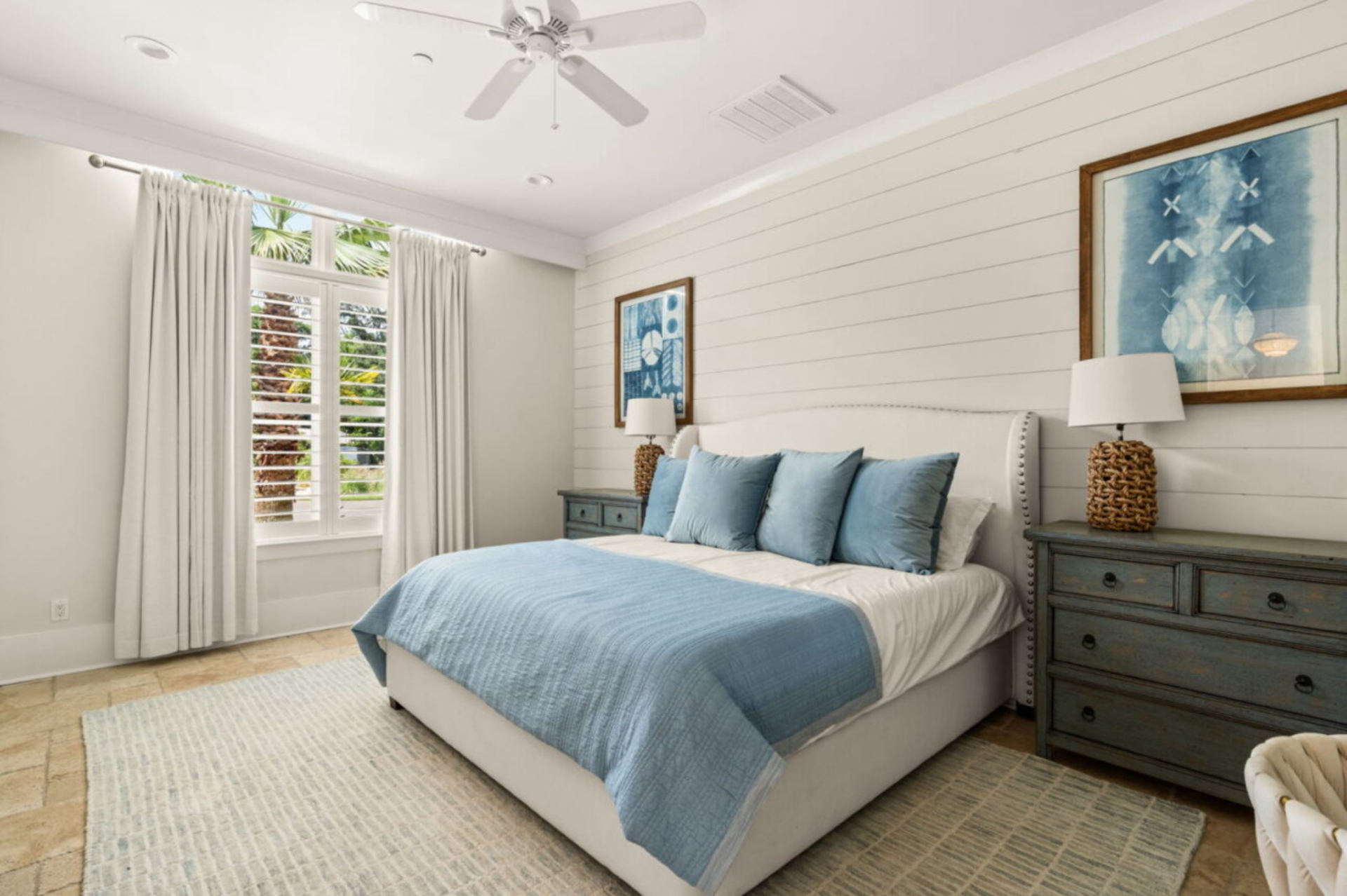 Another bedroom carries a more relaxed coastal look with horizontal white shiplap walls and soft blue accents.