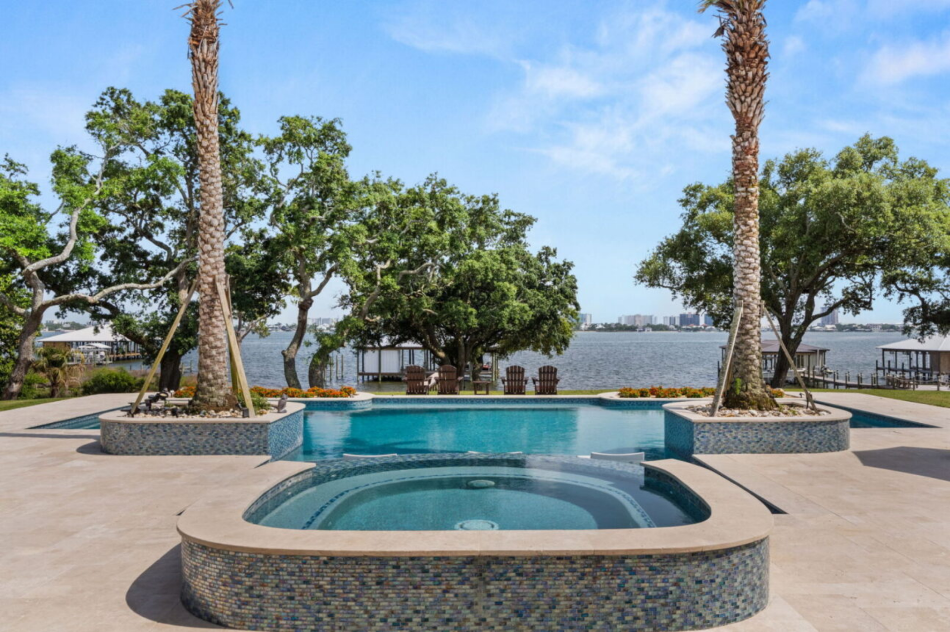 A circular spa sits in the foreground, while shallow lounging areas and poolside seating provide space to relax and take in the open views across the water.