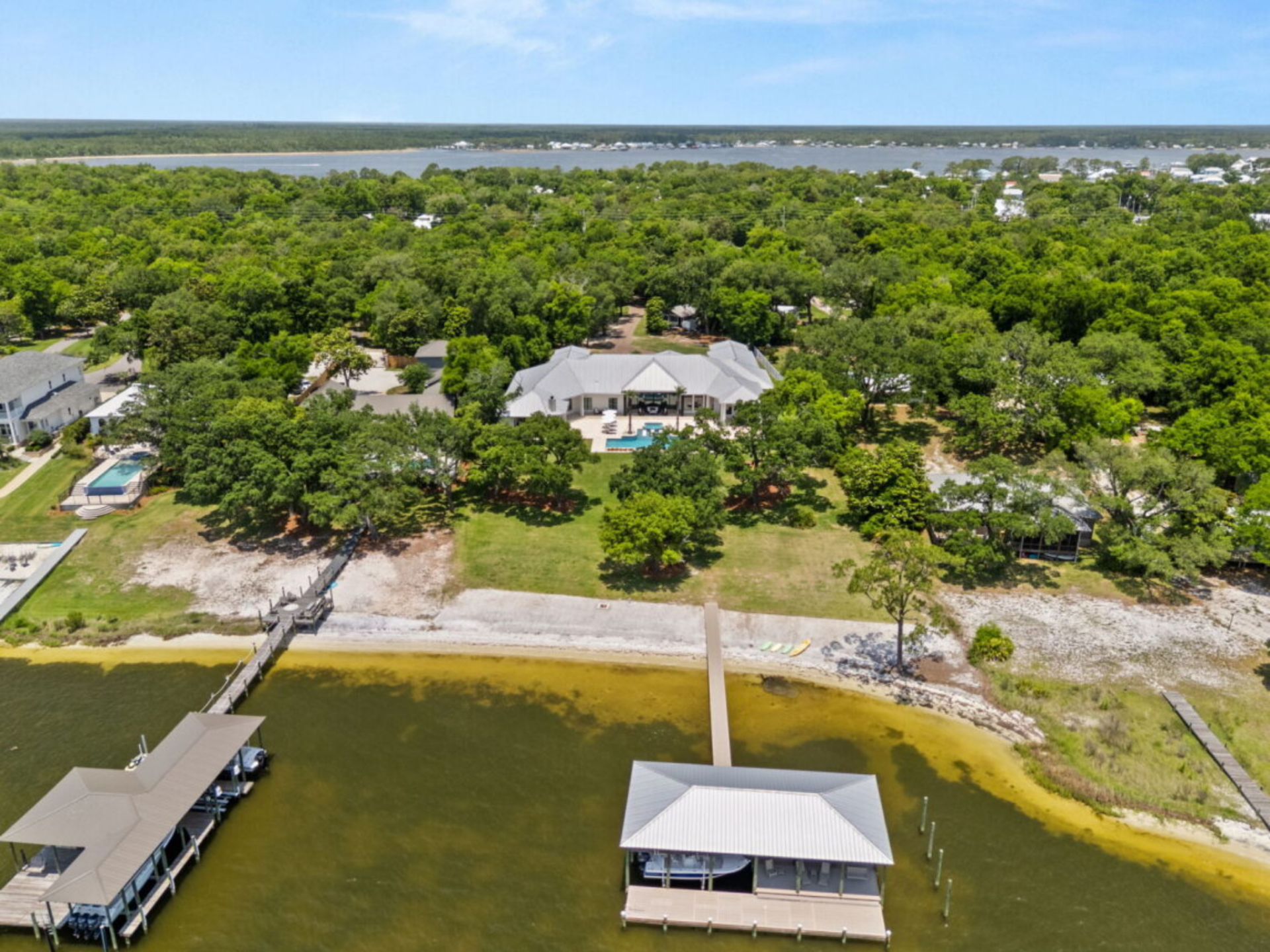 A long dock leads to a covered boat house positioned over the water, offering direct access for boating and water activities.