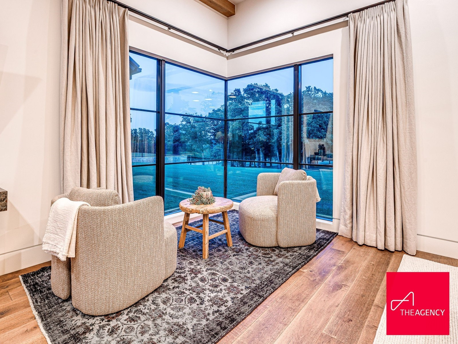 A sitting area is positioned near the glass, creating a quiet space facing the landscape.