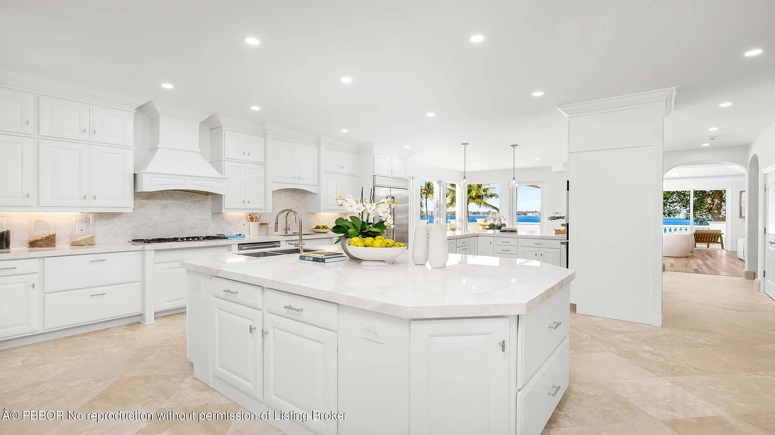 Around the corner, the kitchen features white cabinetry that stretches across the walls with crown molding details, paired with light stone countertops and a matching backsplash. 