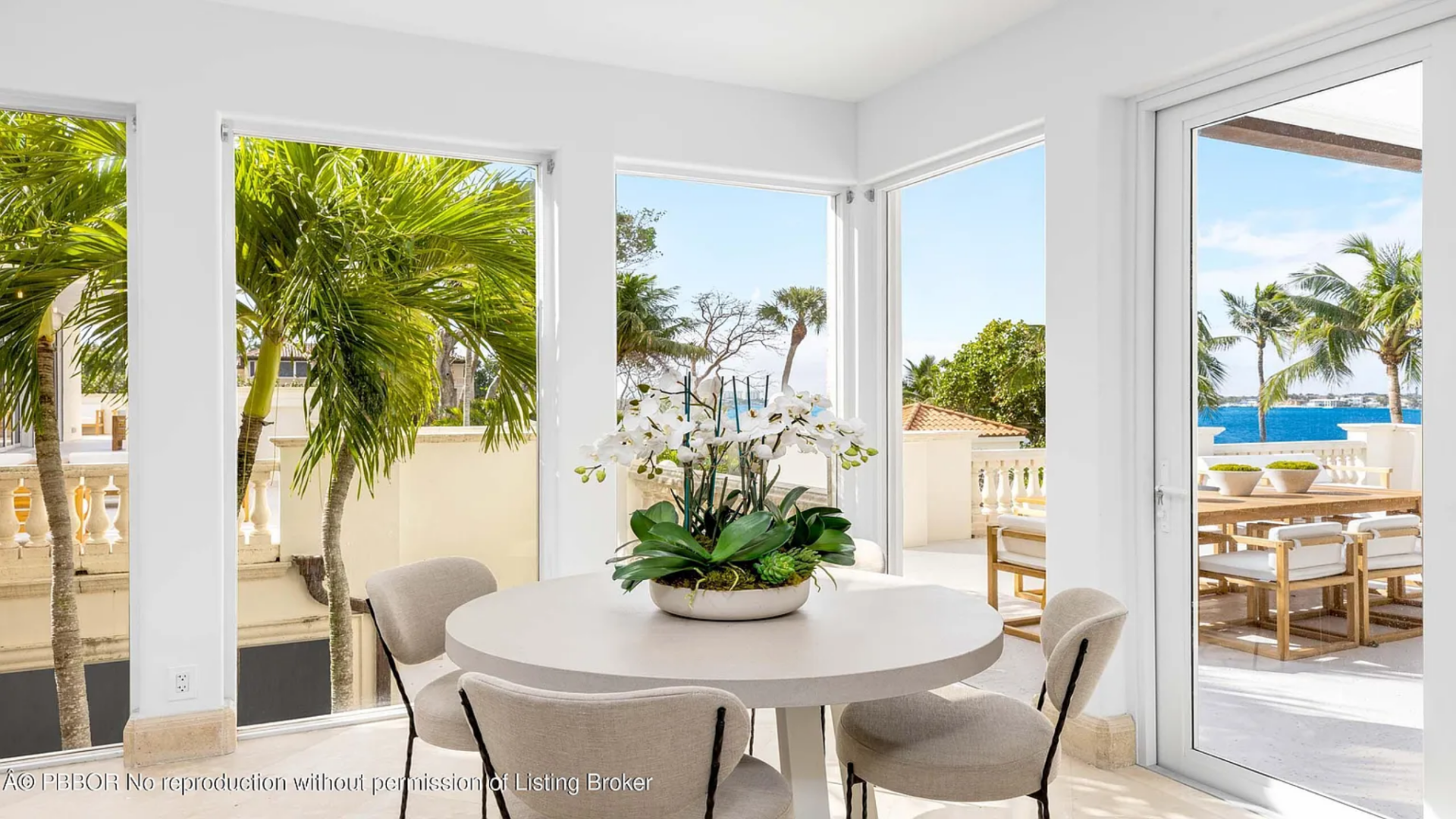 Tucked into a corner surrounded by tall windows, the breakfast nook features a round table positioned to capture views of the palm trees and bay outside. 