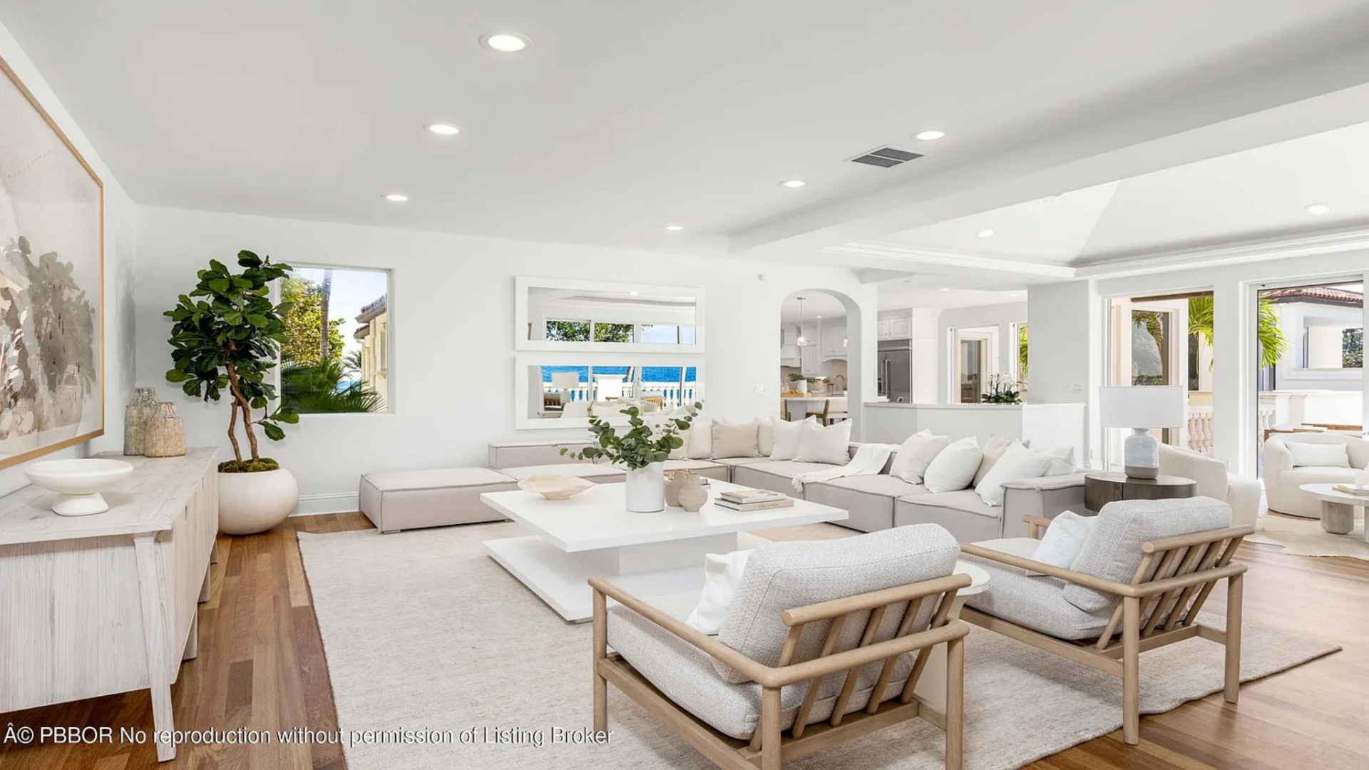 Clean white walls, recessed lighting, and warm wood flooring keep the space bright and simple, while wide openings connect the room back to the kitchen and other living areas.