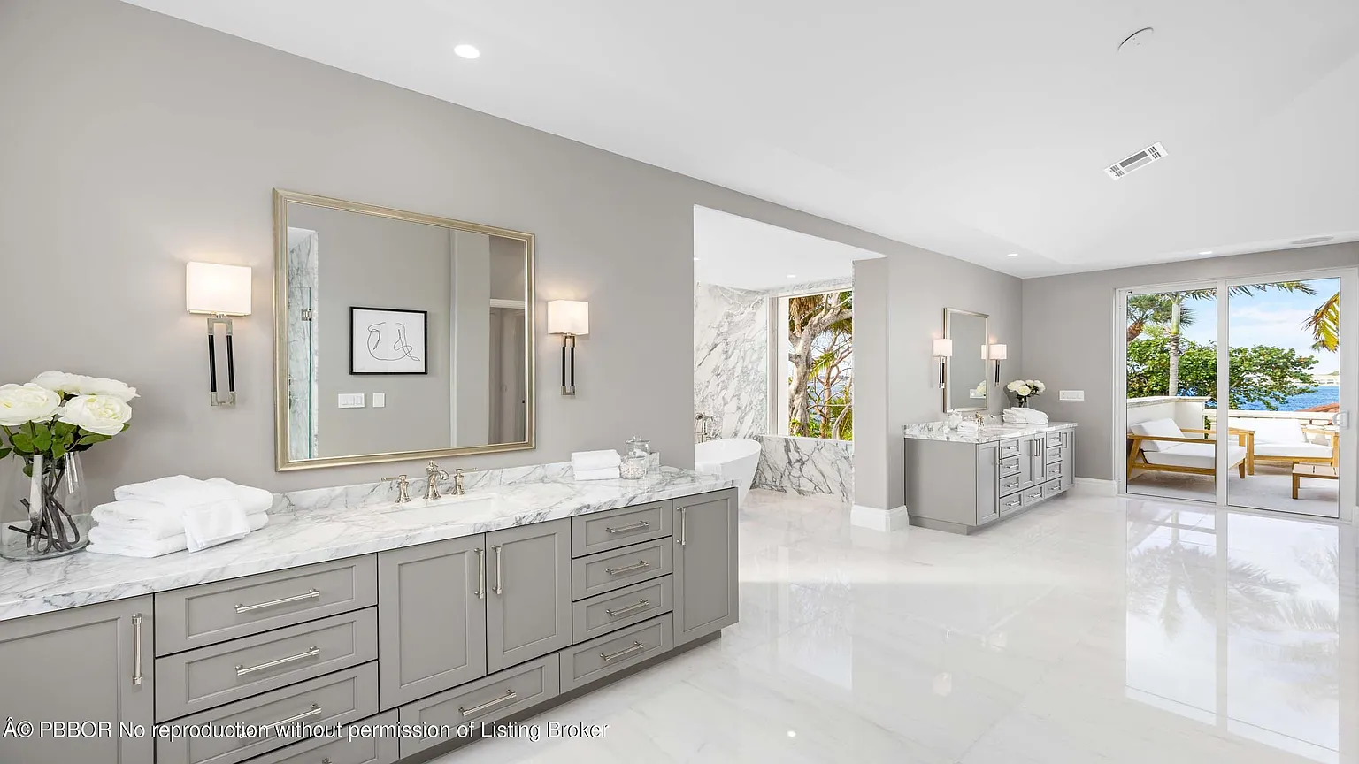 Two large vanities sit on opposite sides of the room, each topped with marble countertops and lined with drawers and cabinetry for storage. 