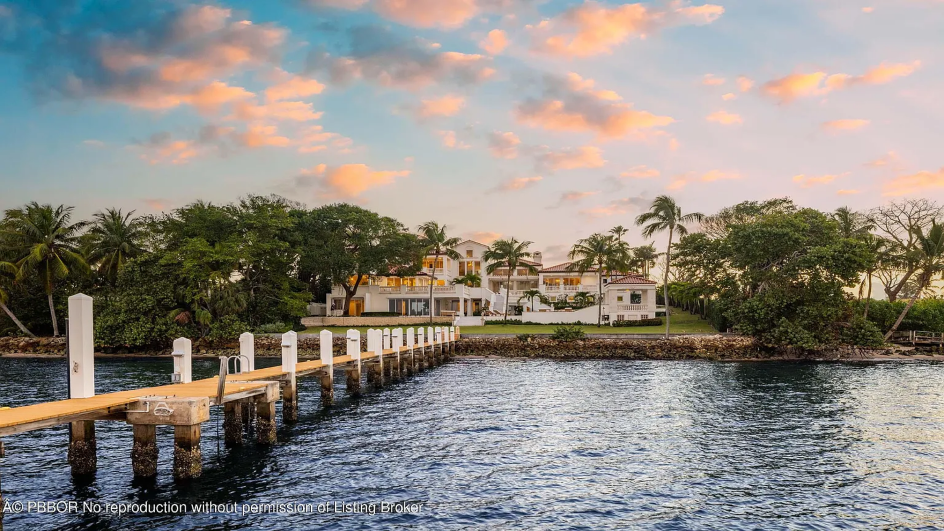 At the water’s edge, a private dock stretches out into the bay, offering direct boating access and clear views back toward the residence.