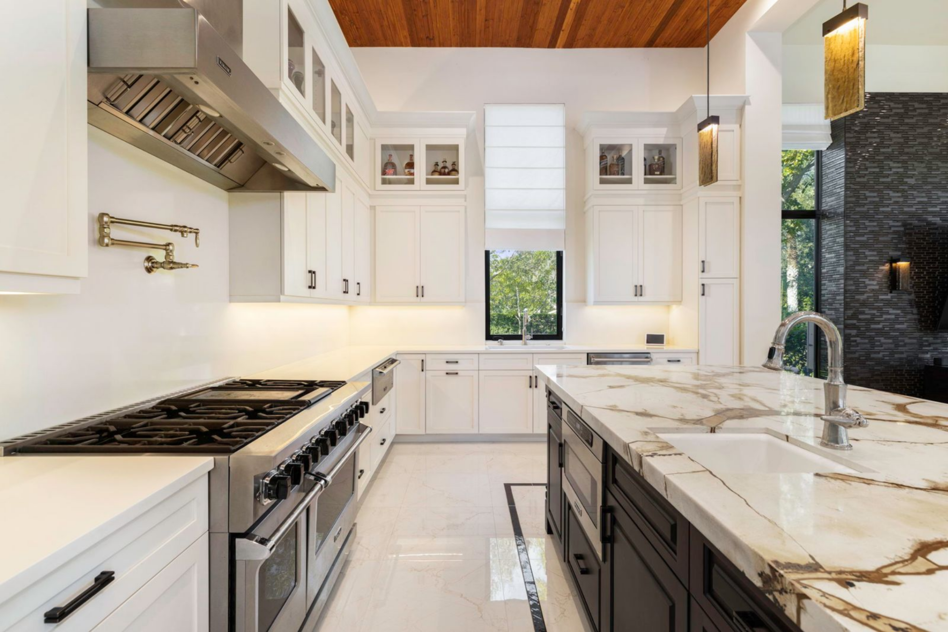 From another angle, the kitchen reveals its full working layout, with long counters, built-in cabinetry, and under-cabinet lighting running along the perimeter. 
