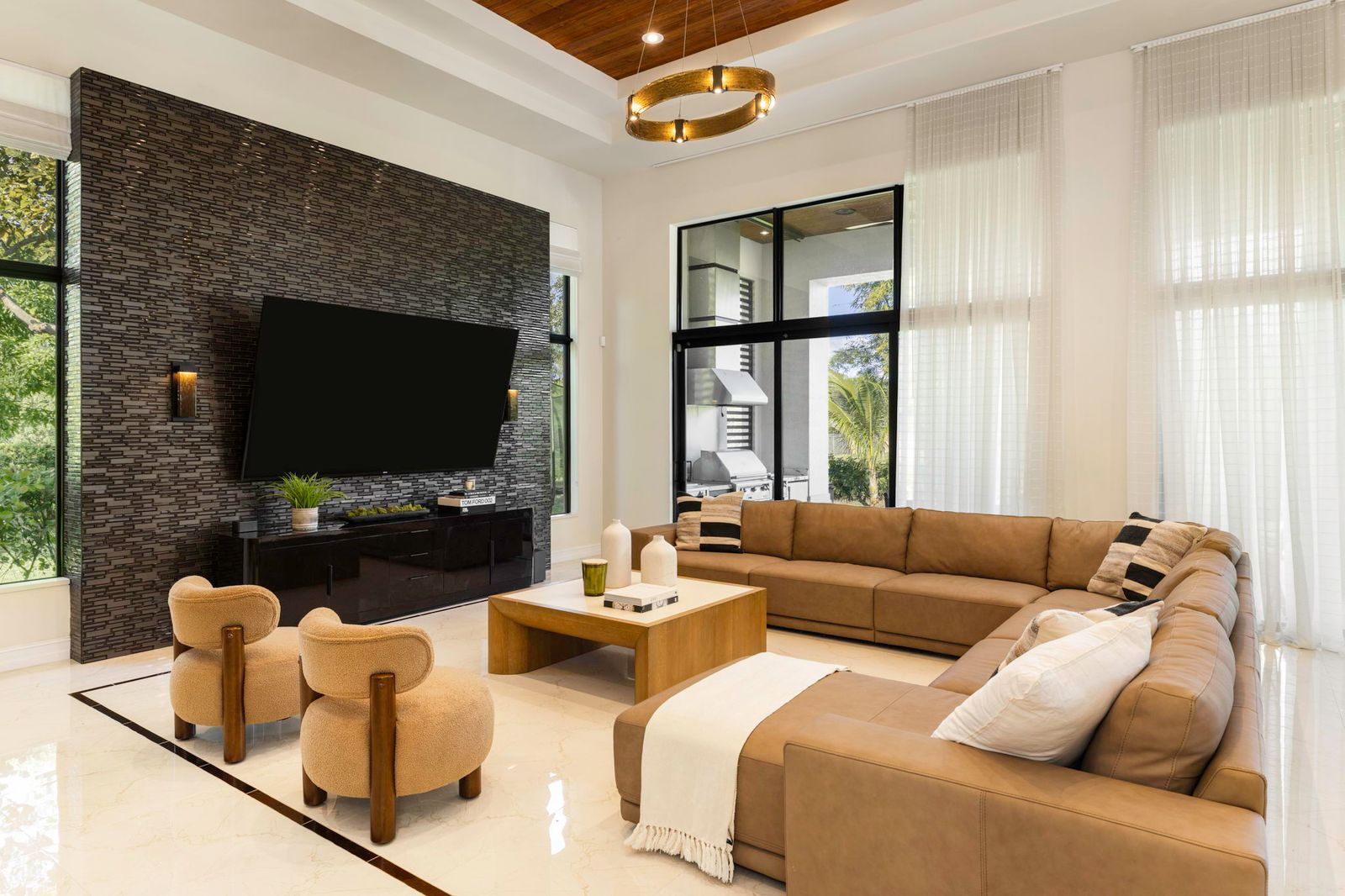 The room is centered around a full wall lined in dark stacked stone that frames a mounted television and media console.