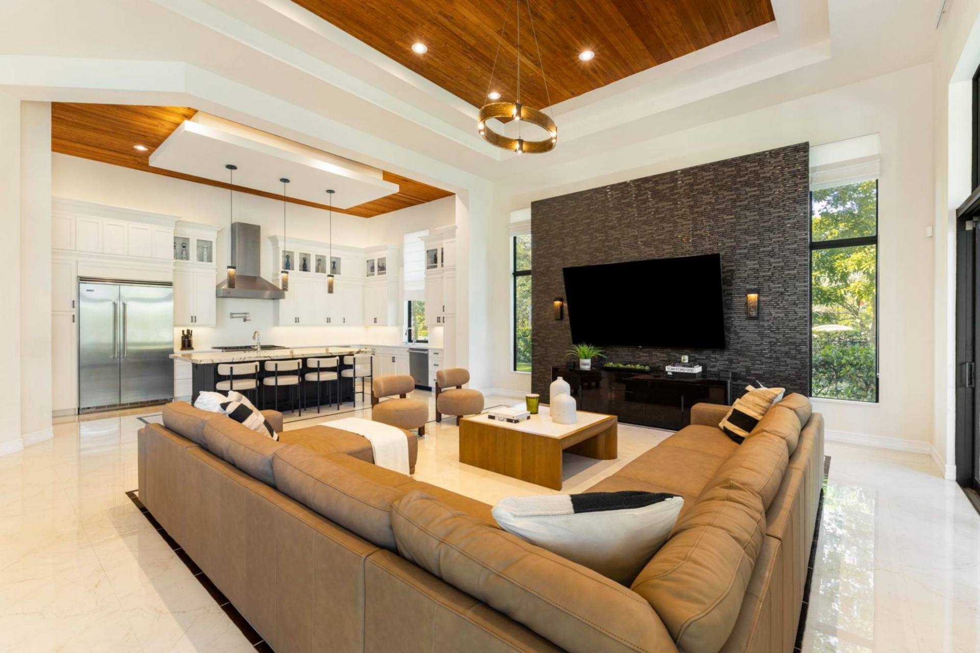 Within the space, a large sectional sofa surrounds a low coffee table, with two accent chairs positioned opposite to create a central gathering area. 