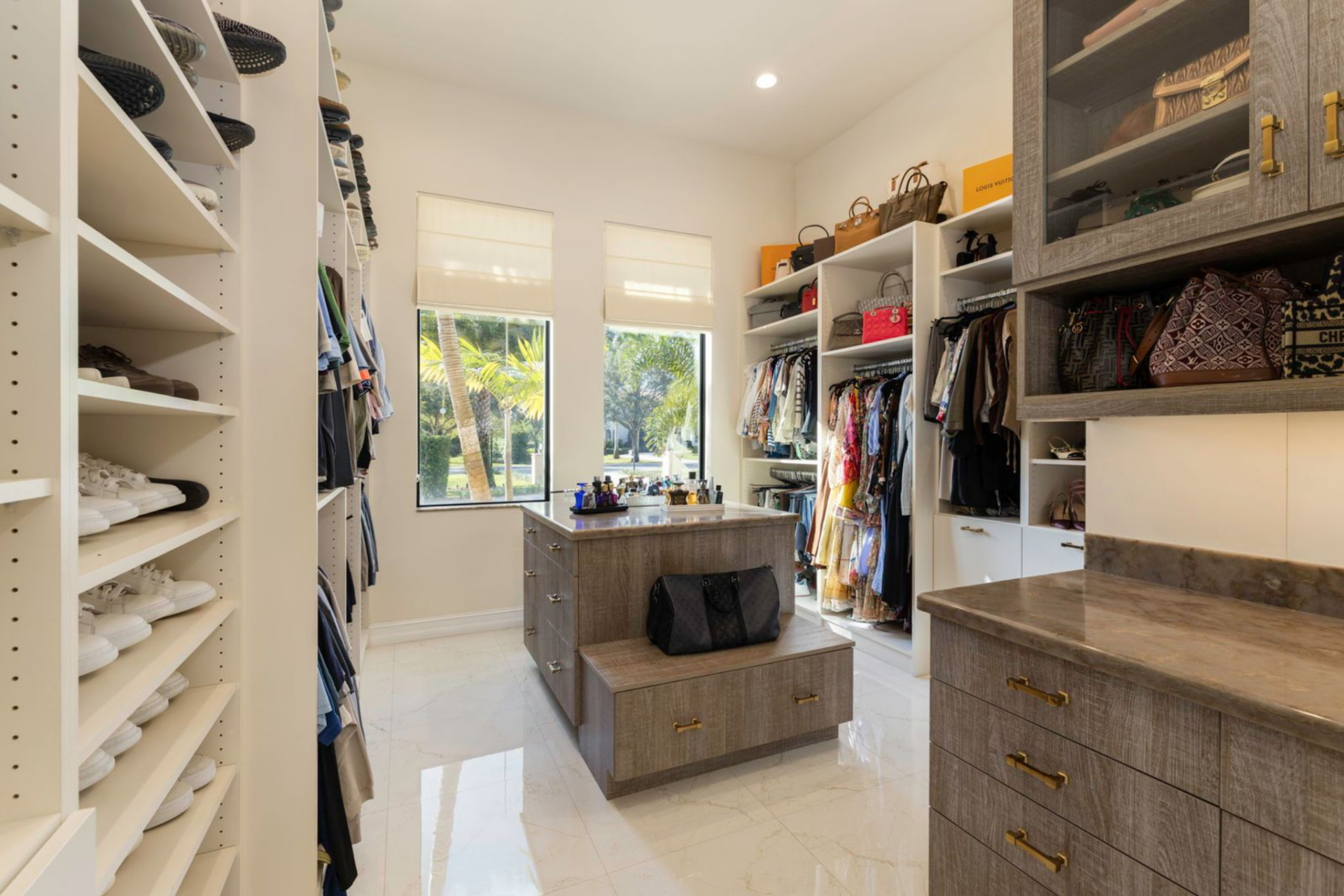 The suite opens into a large custom walk-in closet with built-in shelving, drawers, and display cabinets designed to organize everything from shoes and clothing to handbags and accessories.