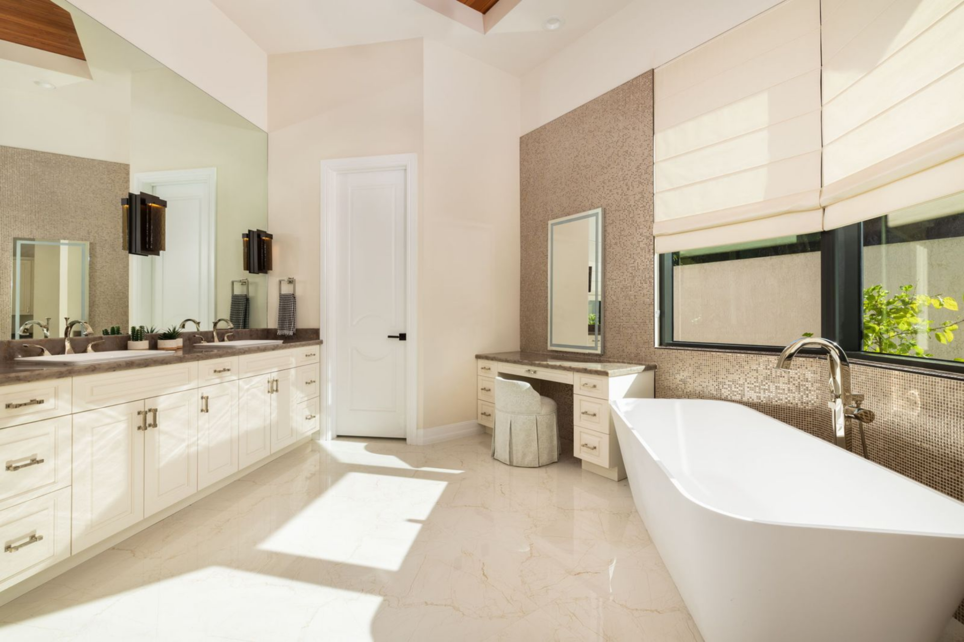 Dual vanities stretch along one side of the room with lots of counter space and storage, while a built-in vanity area offers a dedicated spot for getting ready each day.