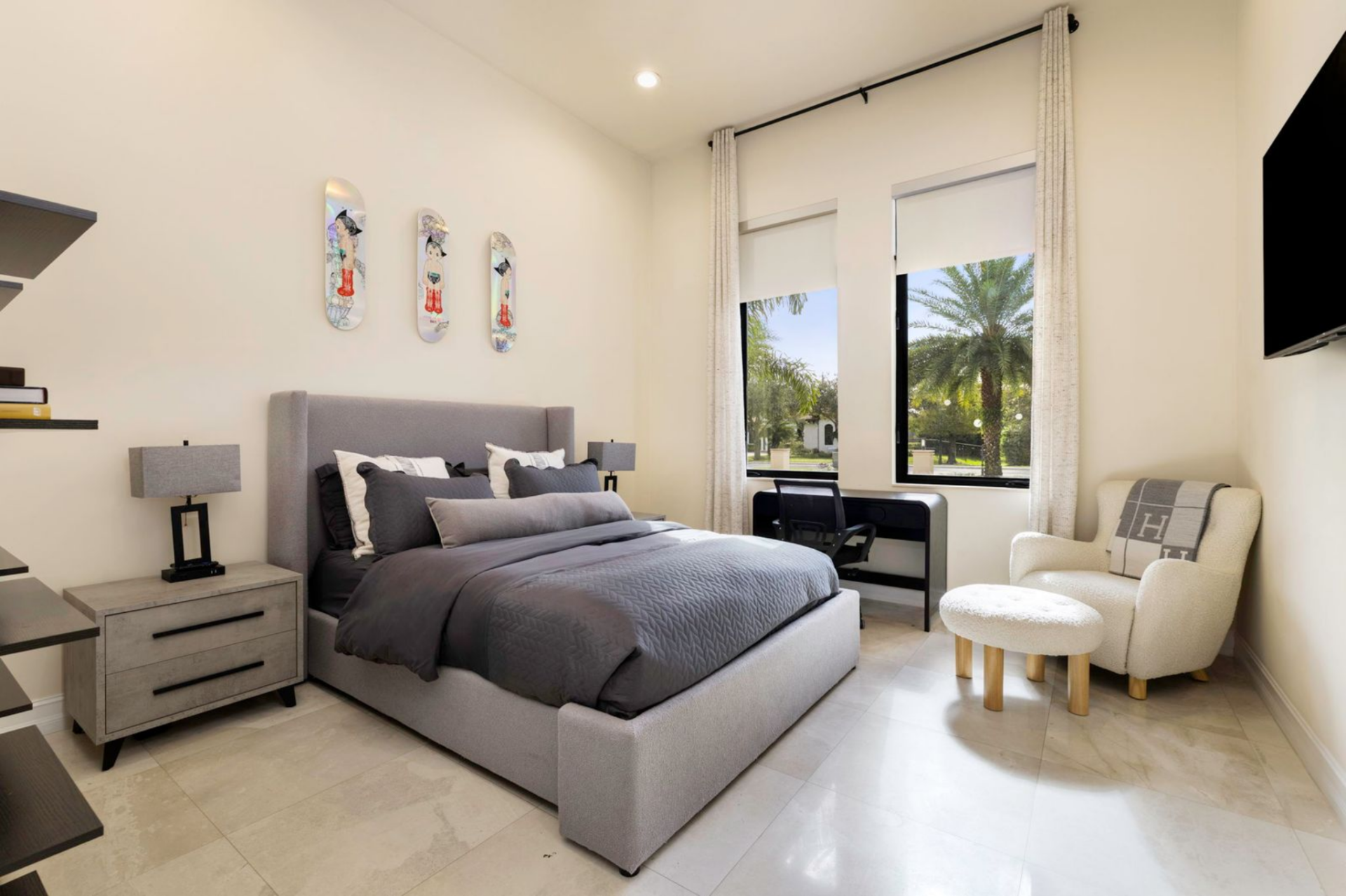 Another bedroom is slightly more contemporary, featuring a gray upholstered bed with layered bedding and sleek nightstands on either side. 