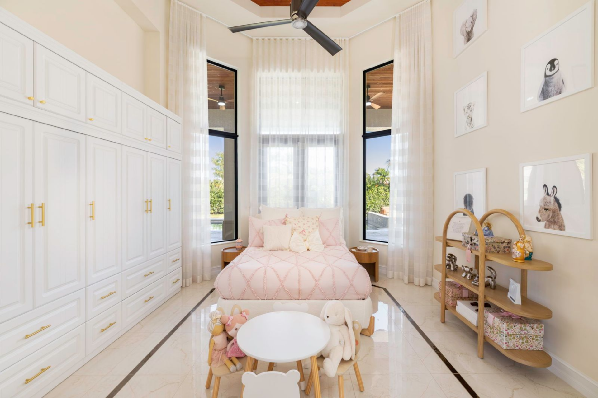 Built-in white cabinetry runs along one wall, while soft pink bedding and child-friendly décor make the room suited for younger guests.