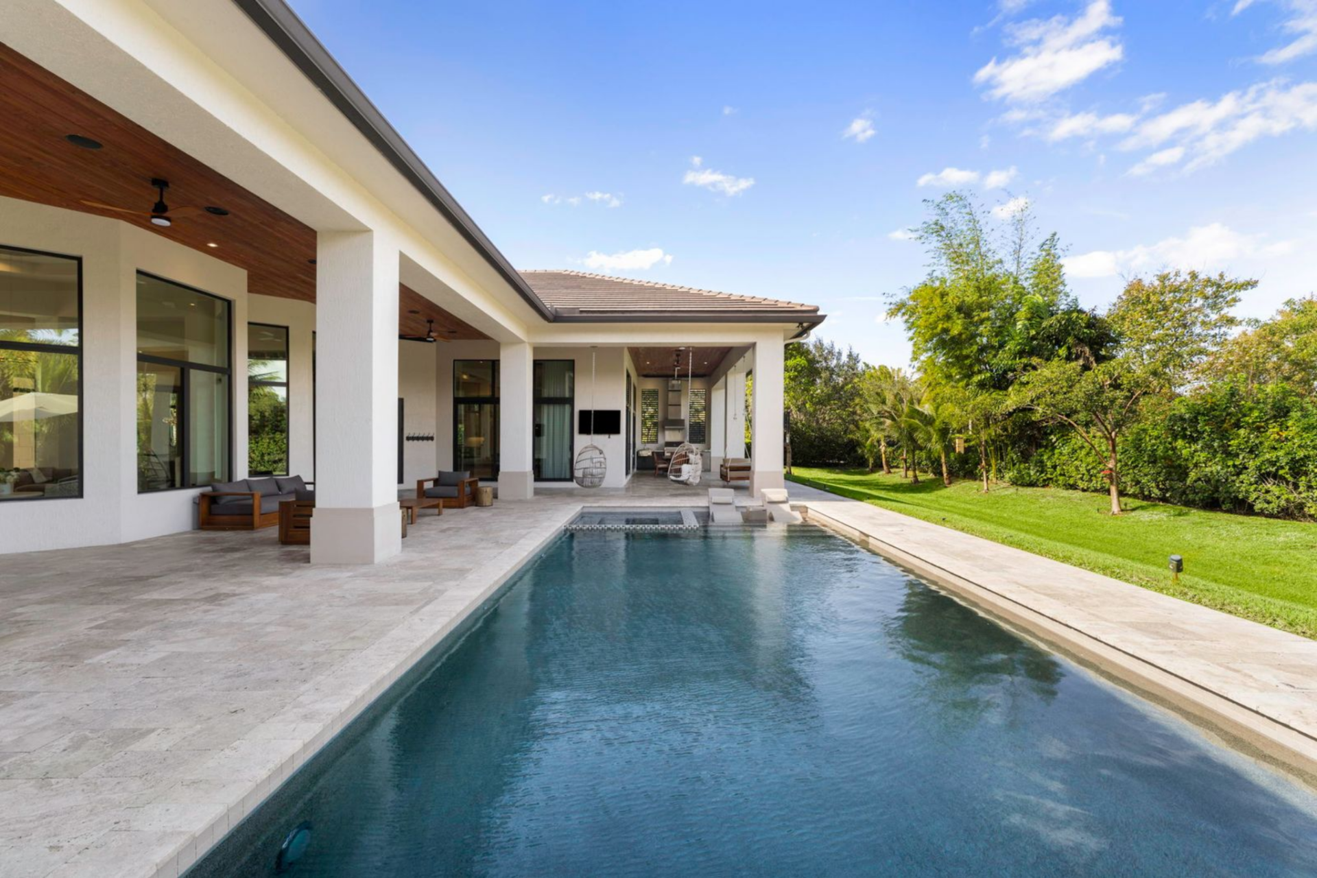 The backyard itself stretches beyond the pool, bordered by fruit trees that add privacy and greenery around the property.