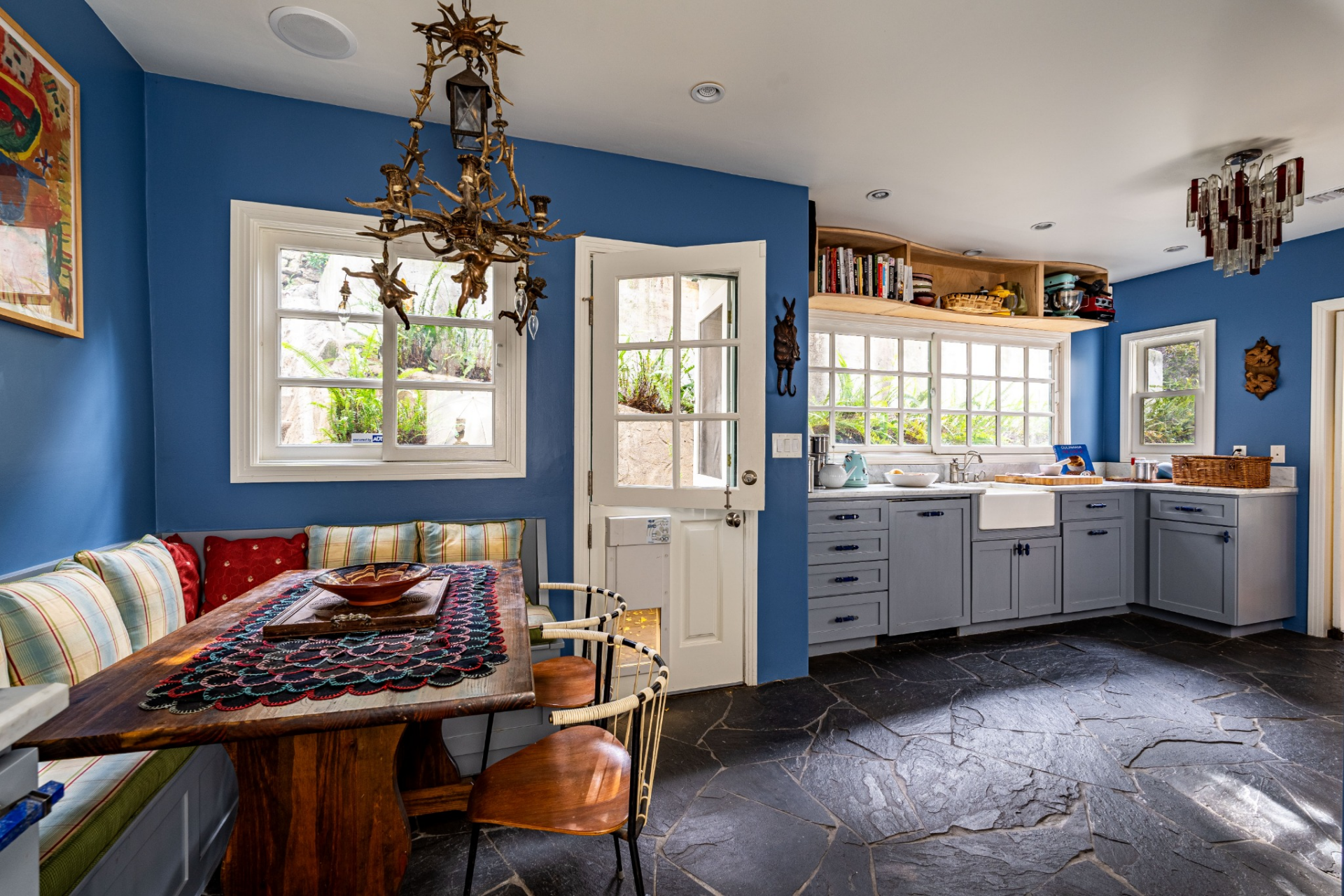 Around the corner, the kitchen continues the home’s colorful personality with bright blue walls paired with soft gray cabinetry and marble countertops.