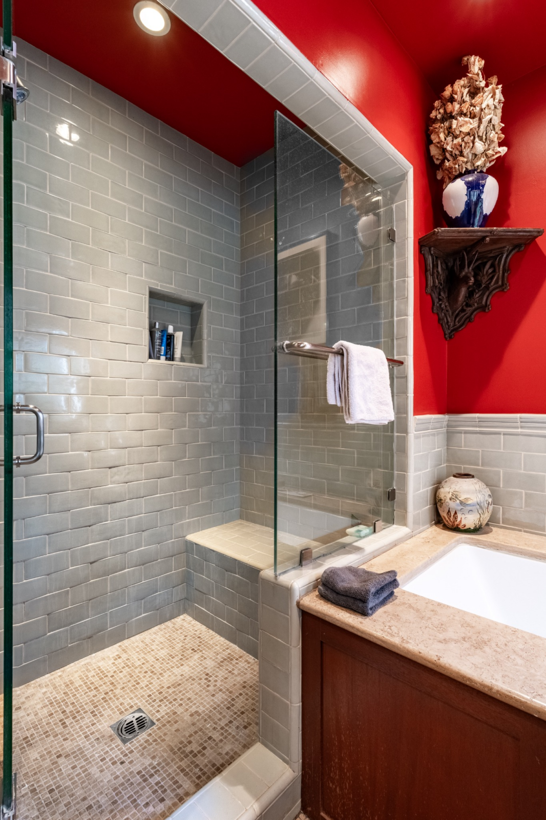 A soaking tub sits between the glass-enclosed shower with a built-in niche and a long vanity that stretches across the room.