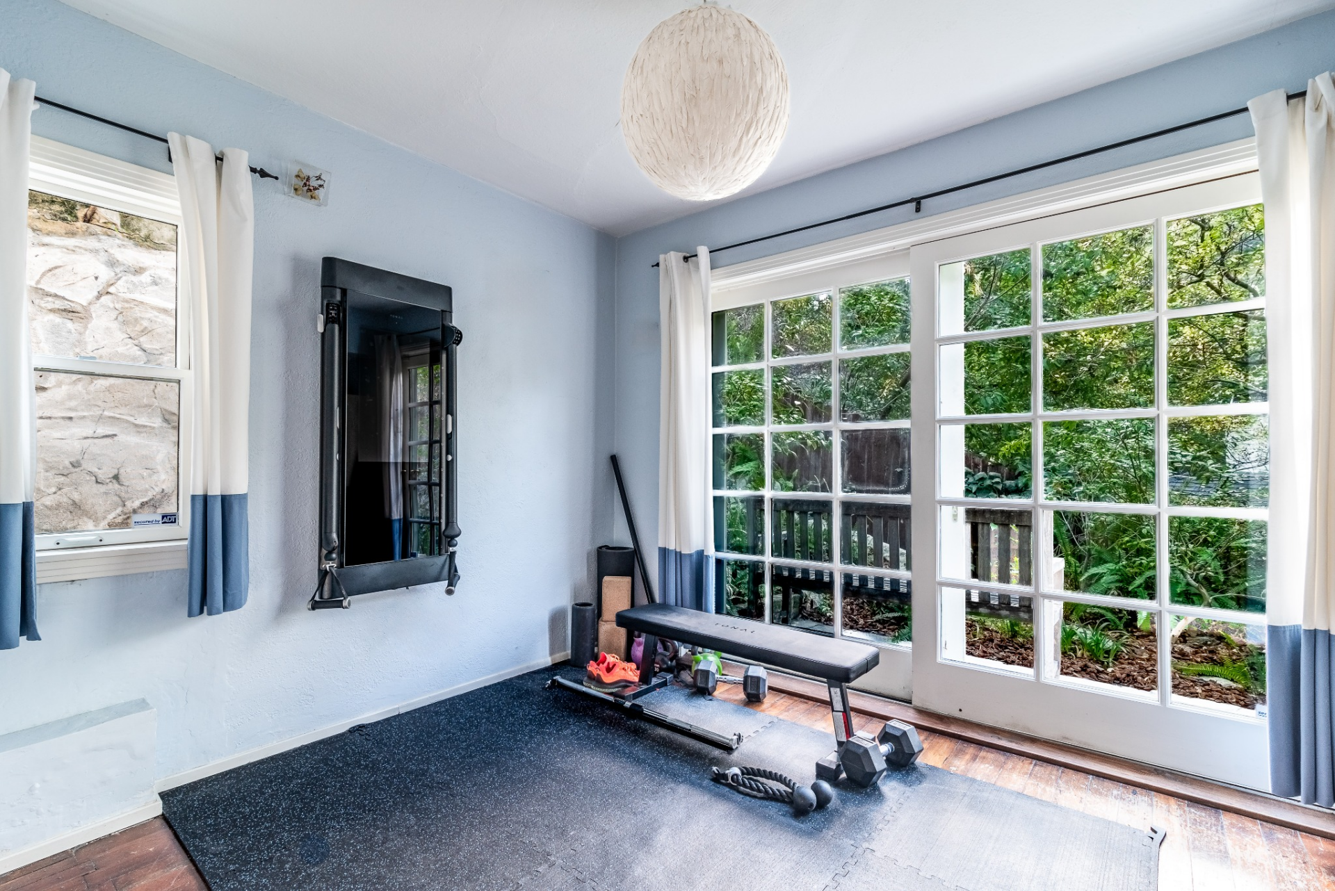The third bedroom is currently set up as a workout space, with large windows and glass doors offering easy outdoor access.