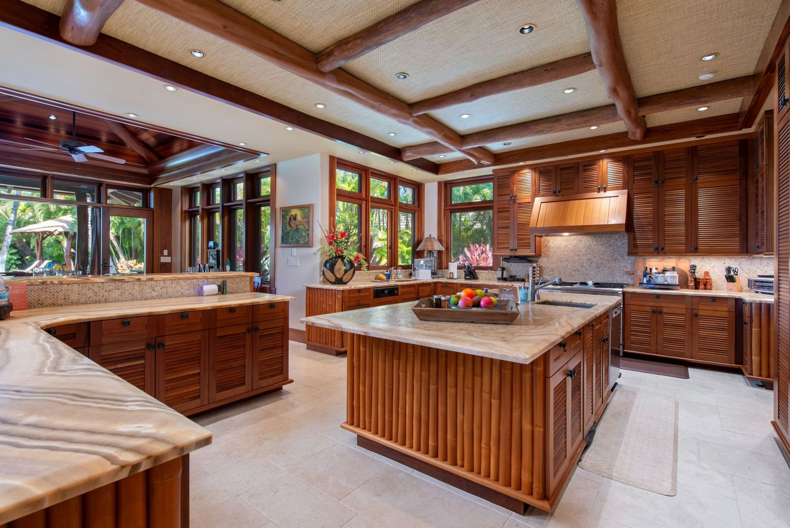 A few steps away, the kitchen has a large central island surrounded by extensive African mahogany cabinetry and stone countertops that provide generous prep space.