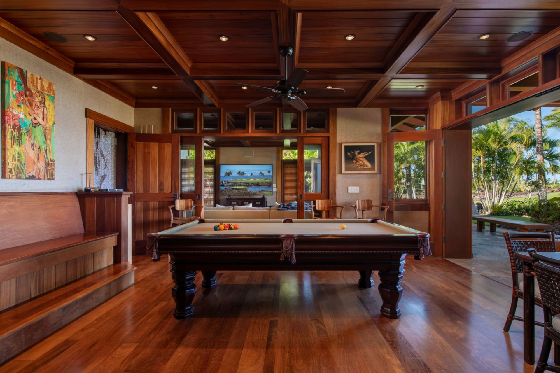 Centered around a full-size pool table, the billiards room is framed by rich wood floors and a coffered wood ceiling with recessed lighting and a ceiling fan.