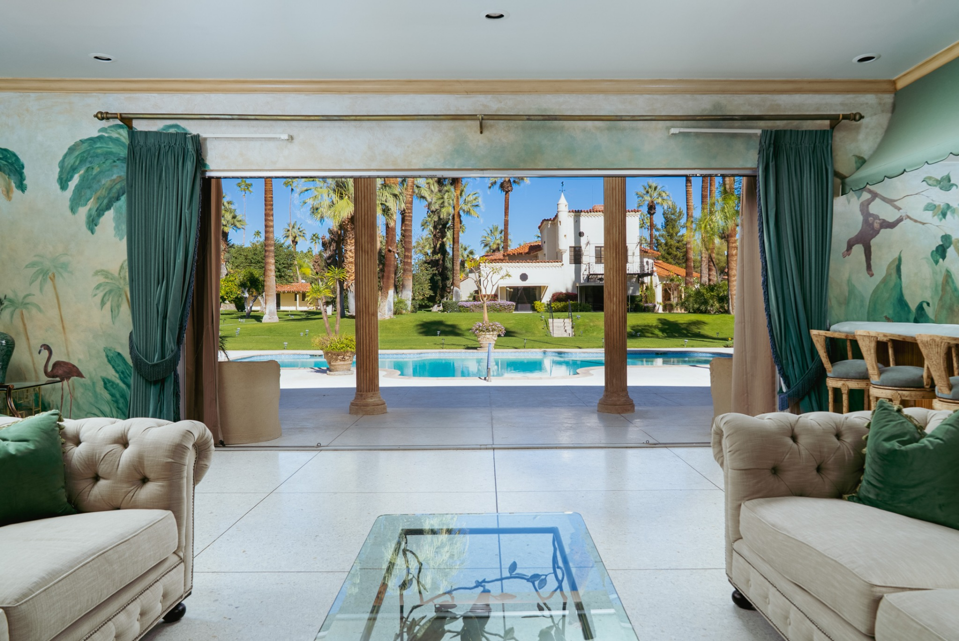 The pool house opens directly onto the pool deck, framing views back across the water toward the main residence and the rest of the grounds.