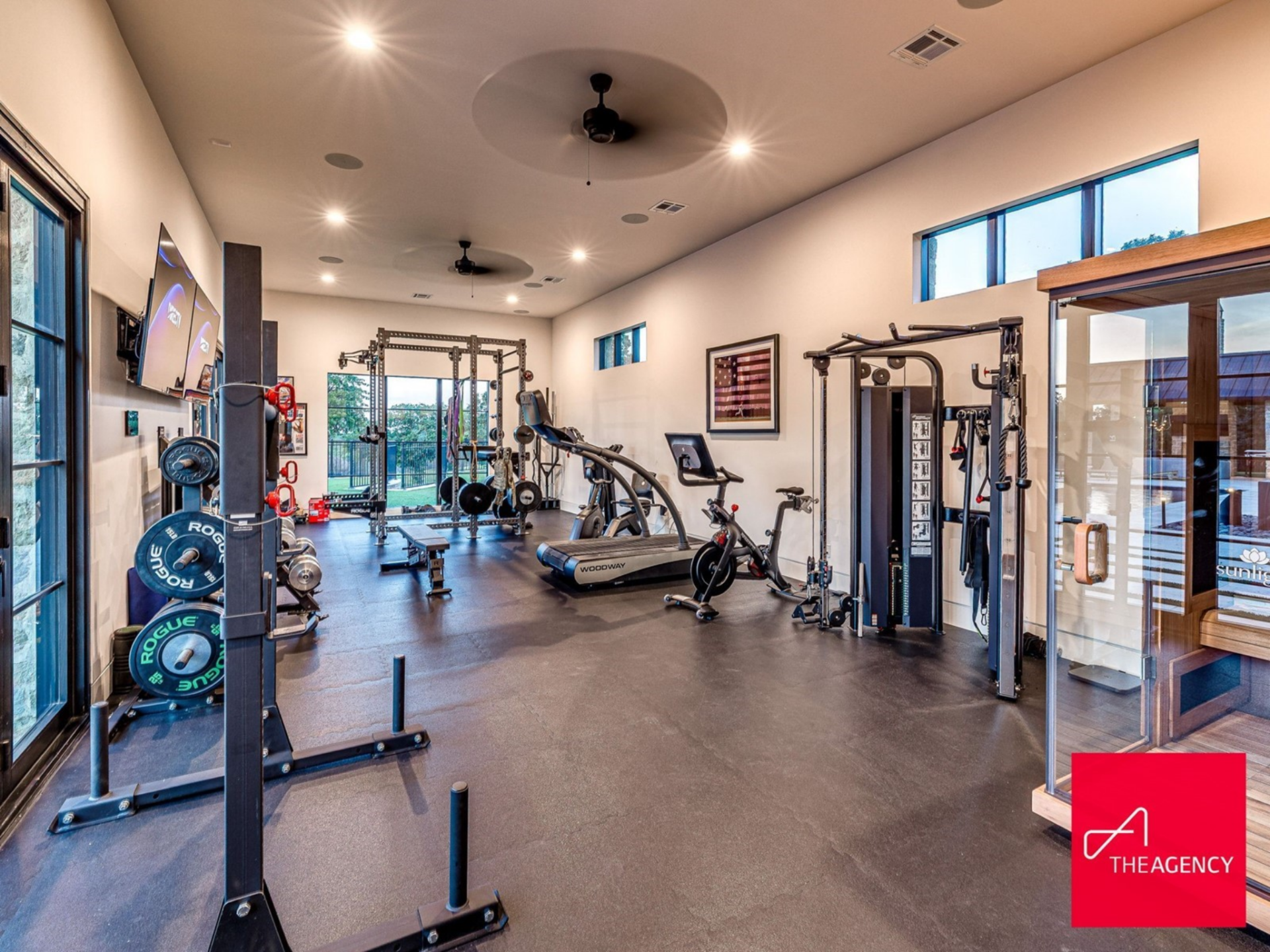 The private gym is equipped with professional-grade machines, free weights, squat racks, and cardio equipment, all set on rubber flooring.