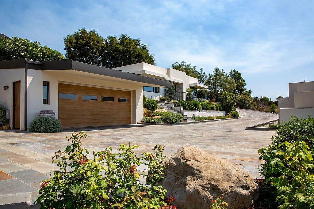 A wide brick motor court separates the main residence from the guest house, creating a central arrival space that defines the layout of the estate. 