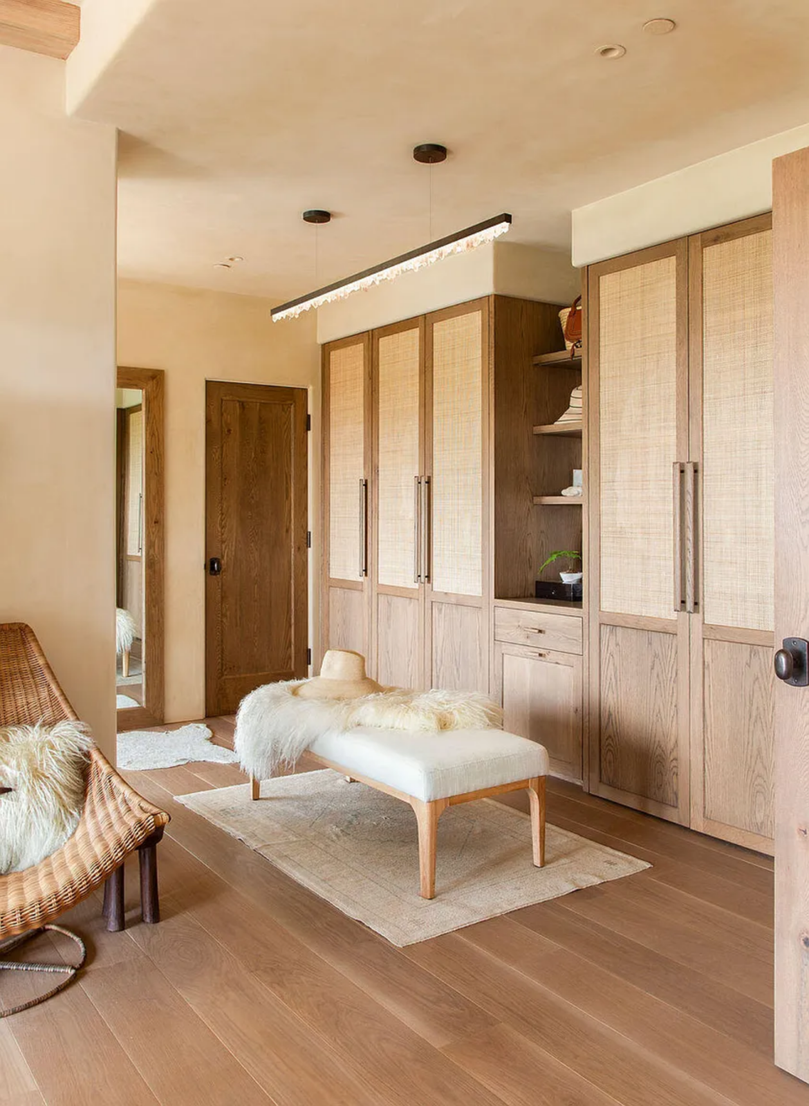 The closets feature paneled doors with woven inserts, open shelving, and integrated drawers, creating a clean and organized space for storage.