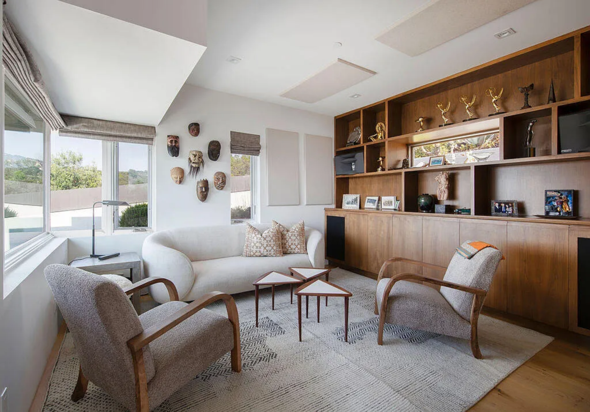 Built-in wood shelving lines one wall, displaying several of his acting awards alongside photographs, memorabilia, and decorative objects. 