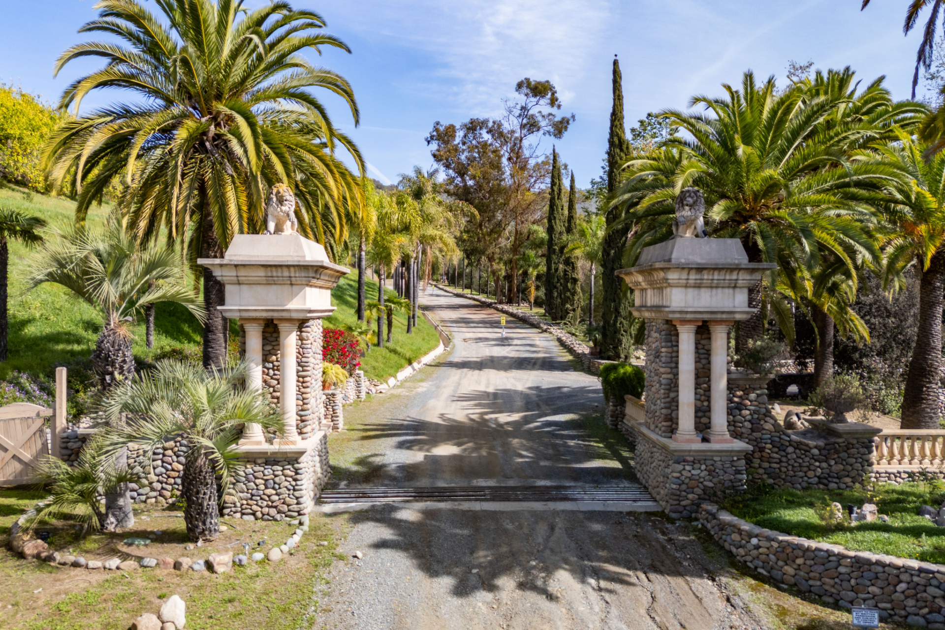 Entry to Maroni Ranch begins at a dramatic gated entrance framed by stone pillars topped with lion statues, setting the tone for the estate beyond. 