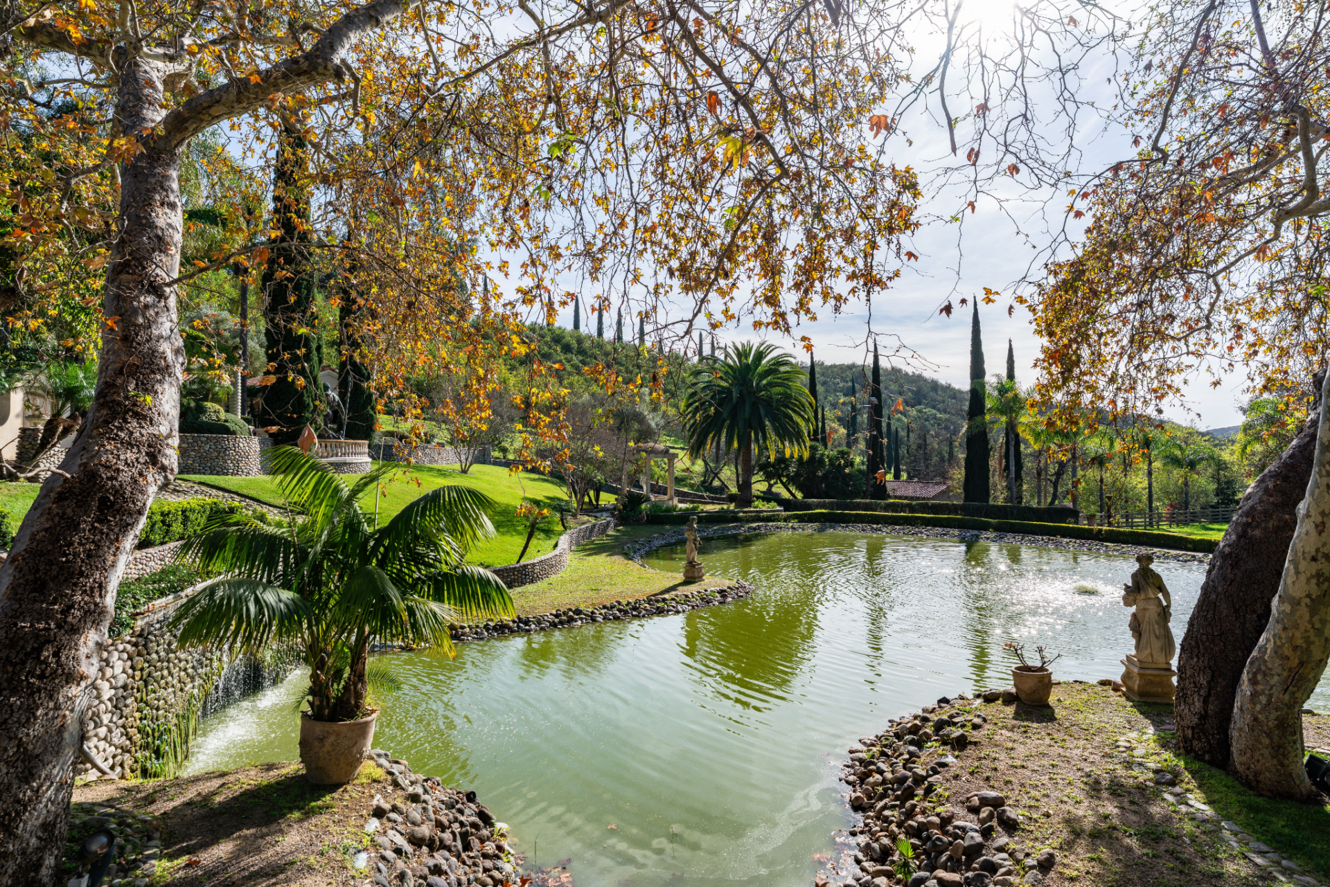 Smaller ponds are scattered across the grounds, including one that stretches directly from the main house terrace, creating a reflective water garden framed by lawns, palms, and layered landscaping.