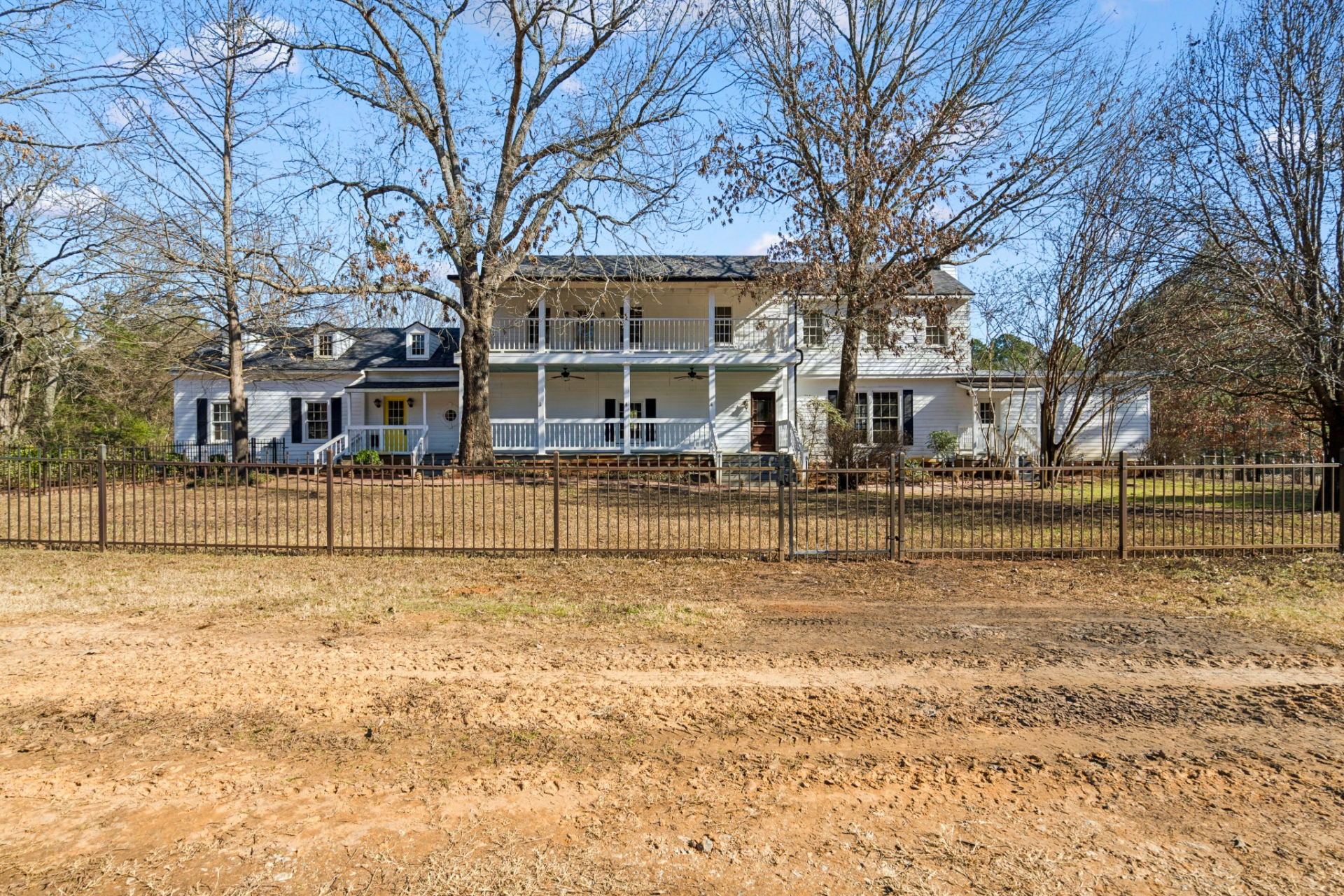 Miranda Lambert’s childhood home starts with a main residence with a classic Southern-style exterior, lined with white siding, a long wraparound porch, and a second-story balcony stretching across the front. 