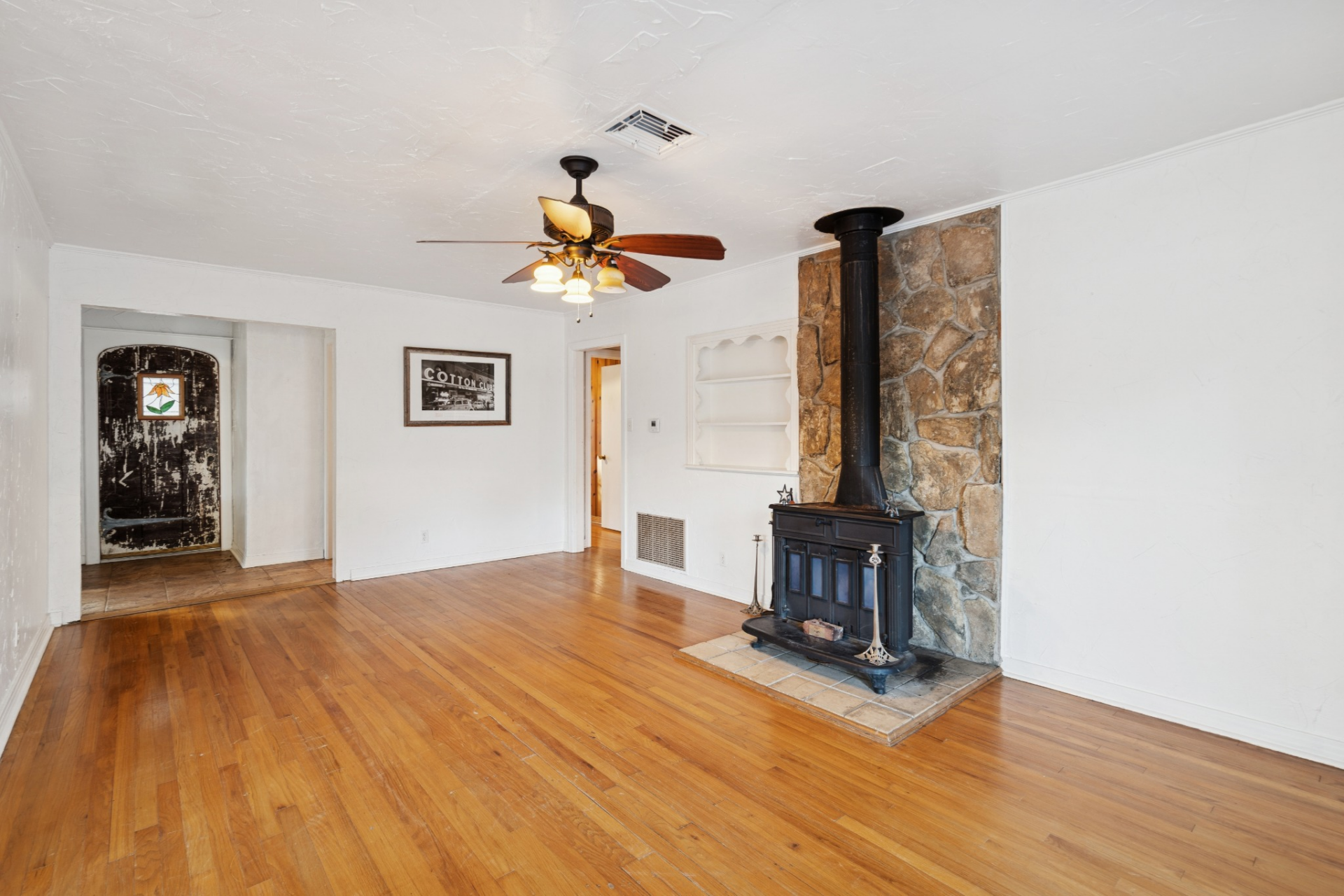 First off, the living room centers around a wood-burning fireplace set against a stone backdrop and sitting next to a small built-in shelf.
