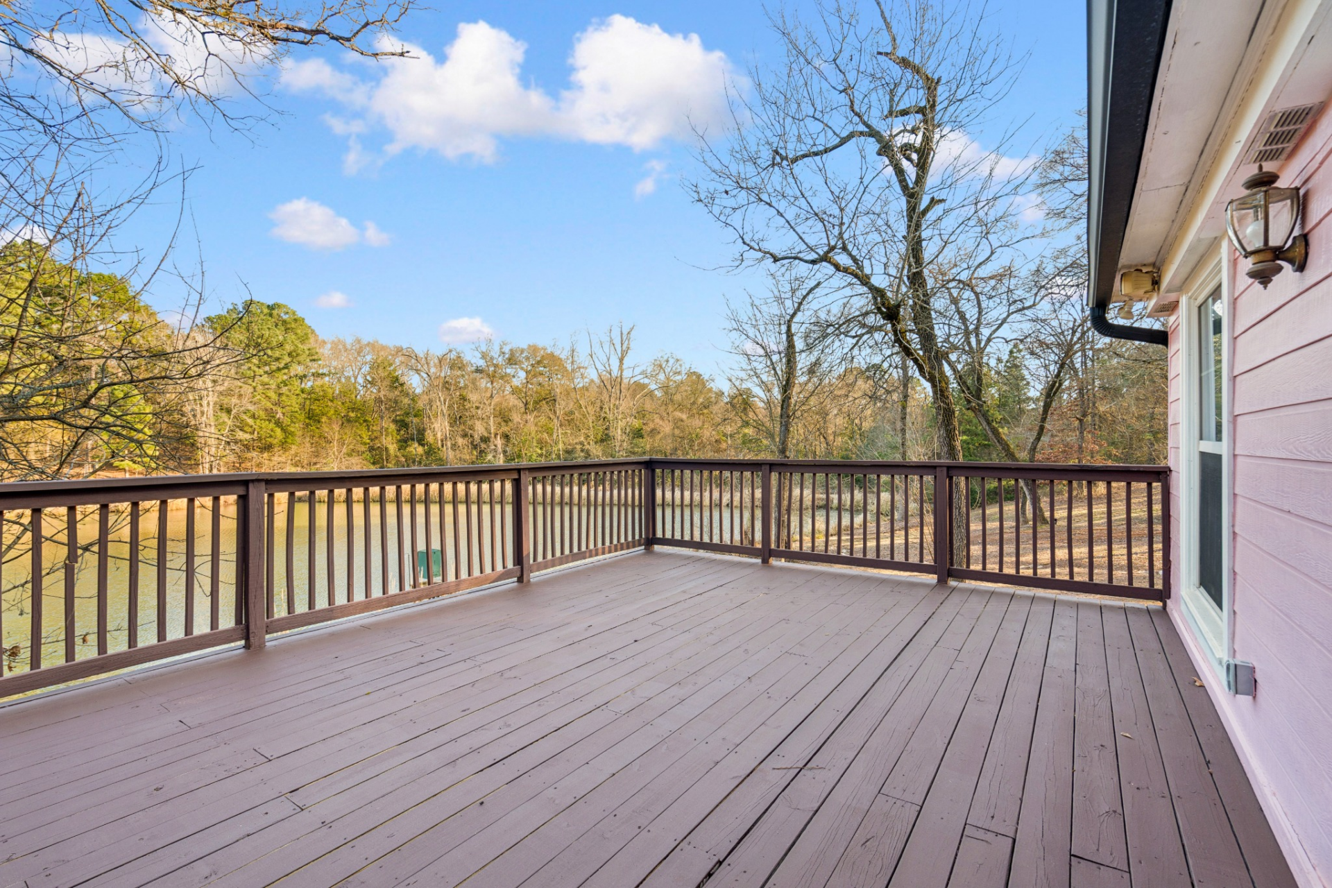 Extending off the back of the home, the deck overlooks the property's pond and the surrounding landscape, framed by a wood railing that runs along the perimeter.