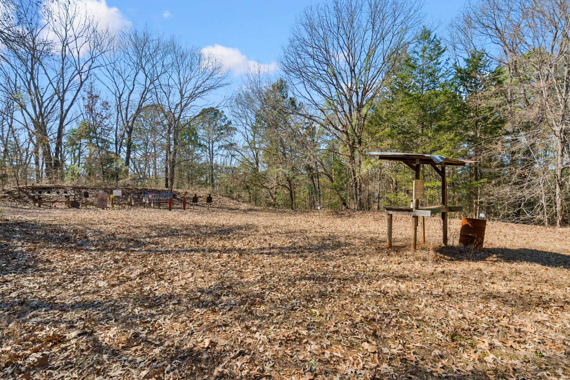 Elsewhere on the grounds, a designated 100-yard shooting range is set apart from the main living areas, with a cleared layout and mounted targets positioned along the tree line. 