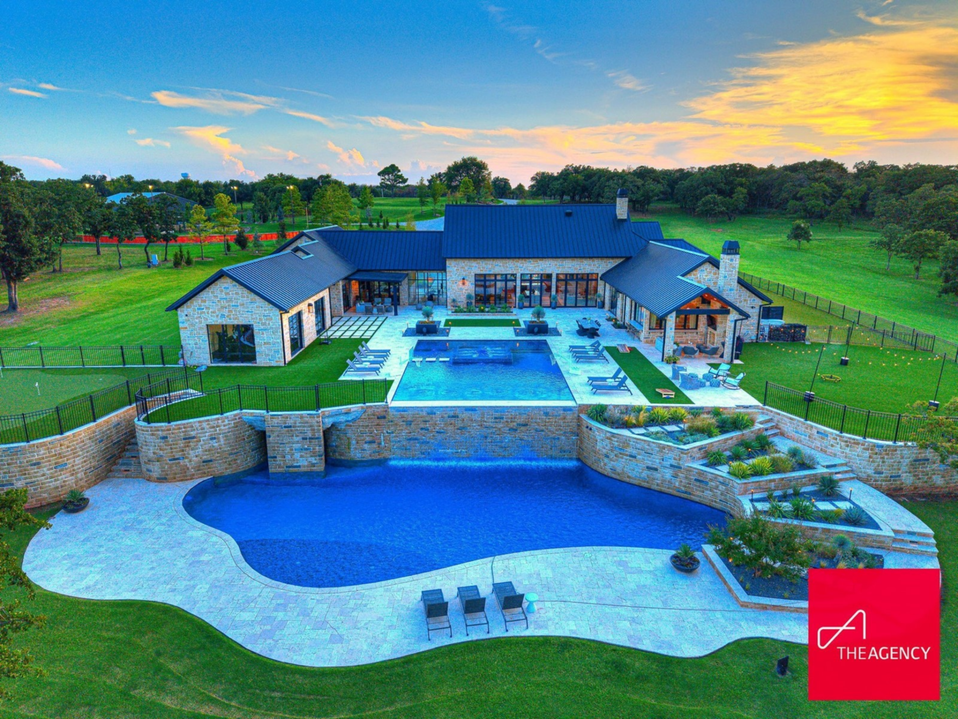 The backyard is centered around a dramatic two-tier pool with a raised upper basin that spills into a larger lower level below.