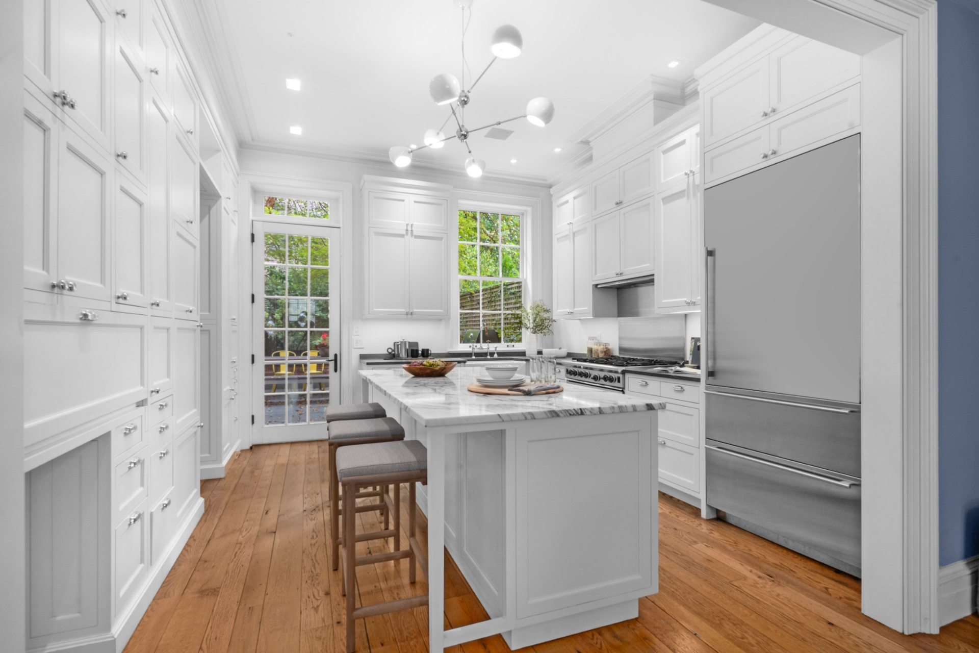 French doors at the far end of the kitchen bring in natural light and connect the kitchen to an outdoor garden.