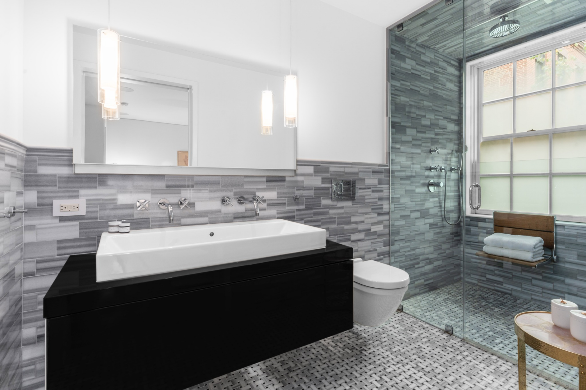 The connected bathroom continues the modern look with a floating vanity, clean-lined fixtures, and a glass-enclosed shower wrapped in gray tile.
