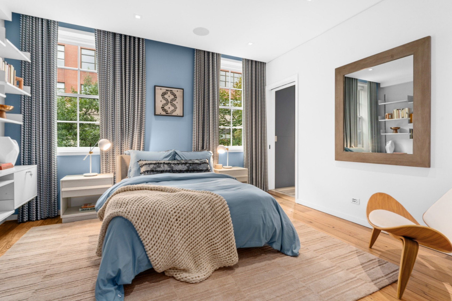 The second suite introduces a richer tone with a blue accent wall that contrasts with the floor-to-ceiling curtains framing the windows and bed.