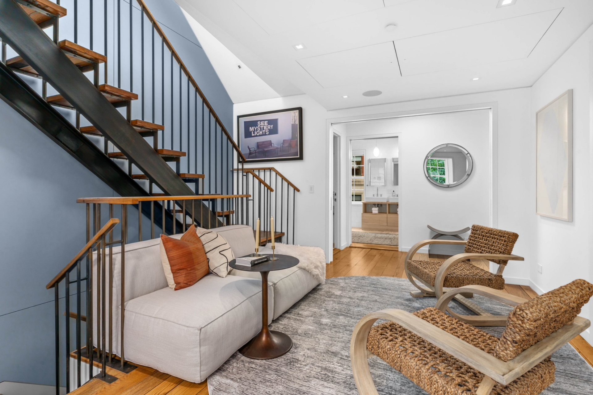 At the top of the stairs, the suite opens into a dedicated lounge with soft, neutral furniture that creates a quiet sitting area before entering the more private spaces.