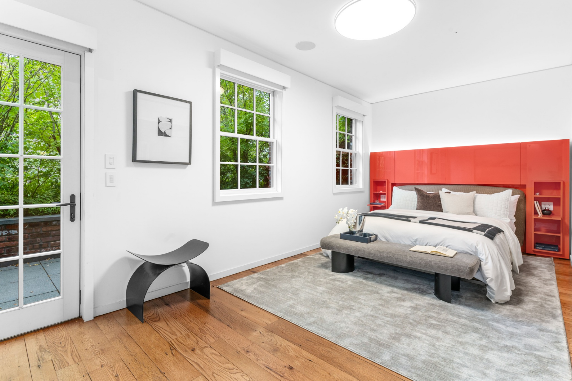 The bedroom itself is centered around a bright red, built-in headboard wall that adds a modern focal point against minimalist decor.