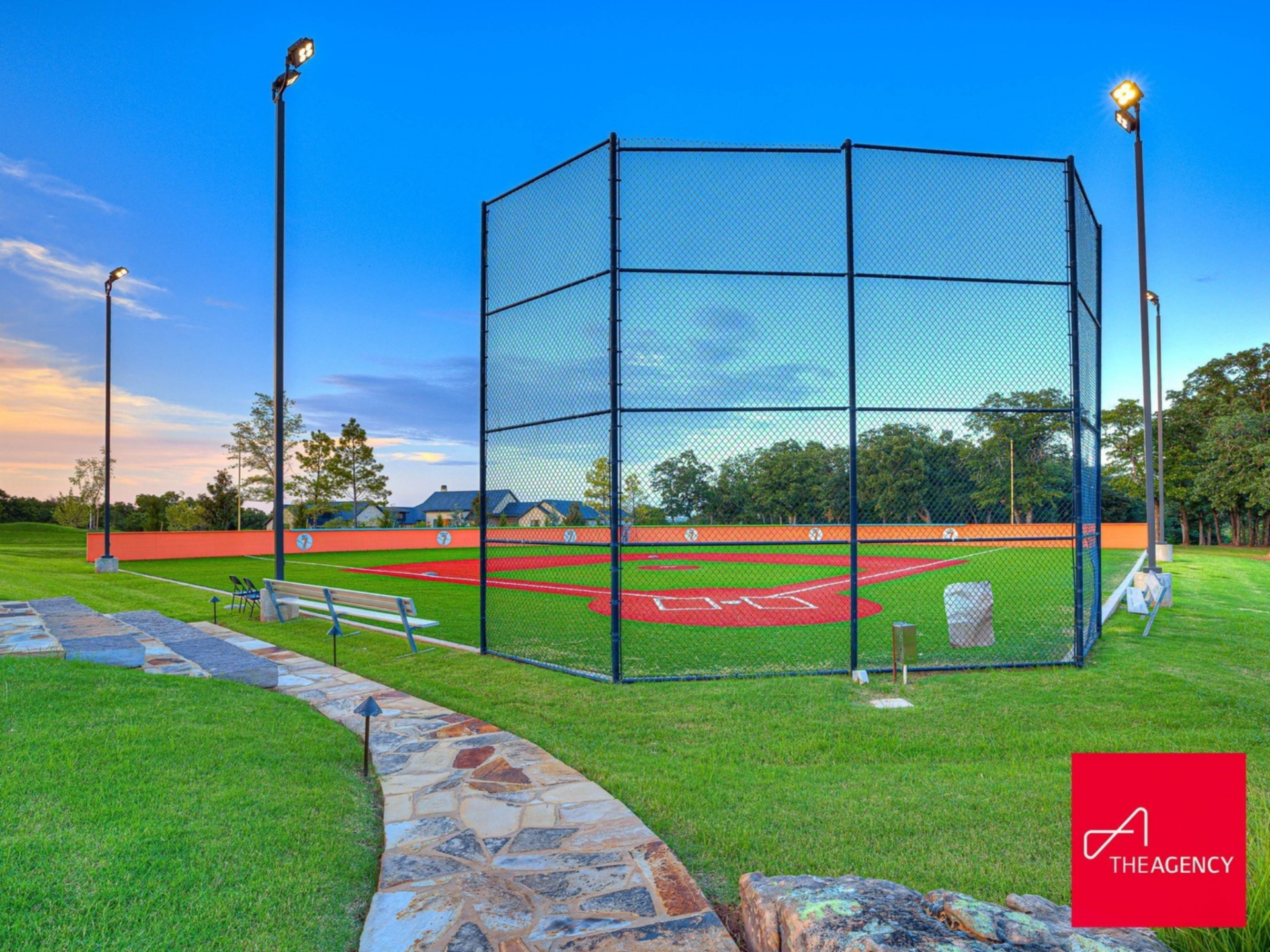 A fully built-out baseball field stretches across the property, complete with turf infield, outfield fencing, stadium-style lighting, and a backstop behind home plate.