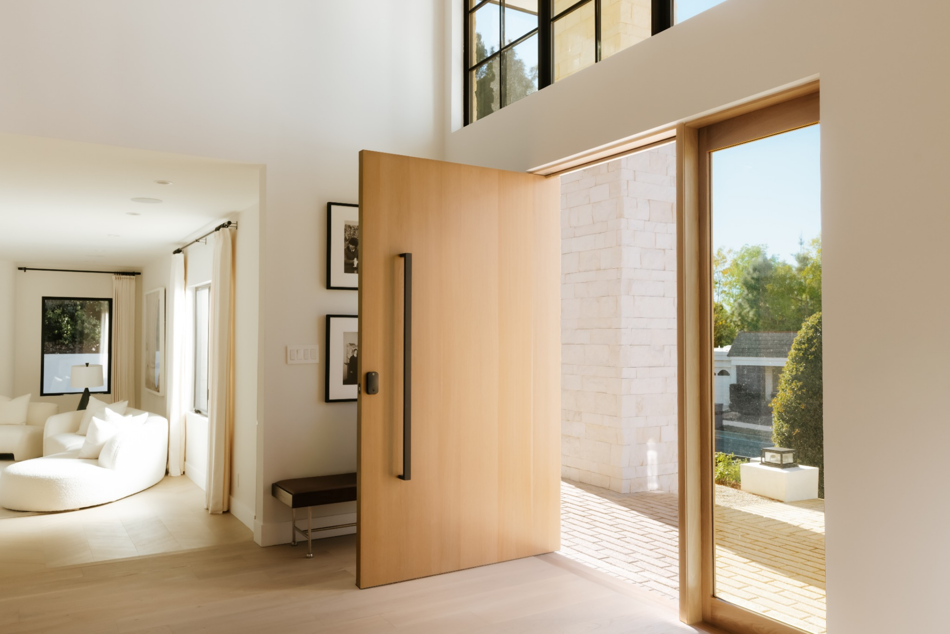 Natural light filters in through oversized glass panels at the entry, carrying through the space and into the rooms beyond. 