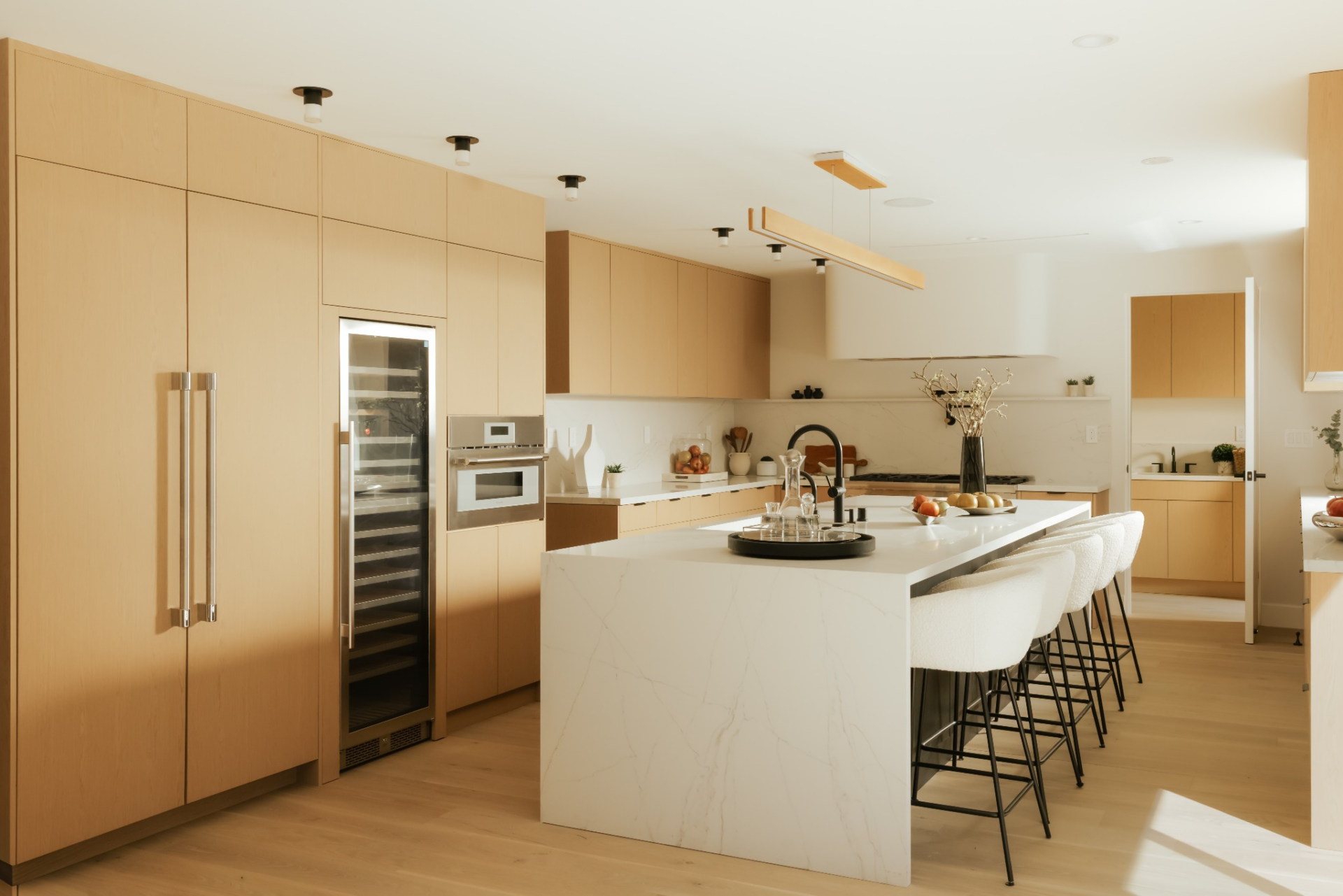Positioned directly behind the family room, the kitchen continues the home’s clean, modern palette with custom flat-panel wood cabinetry that runs wall to wall. 