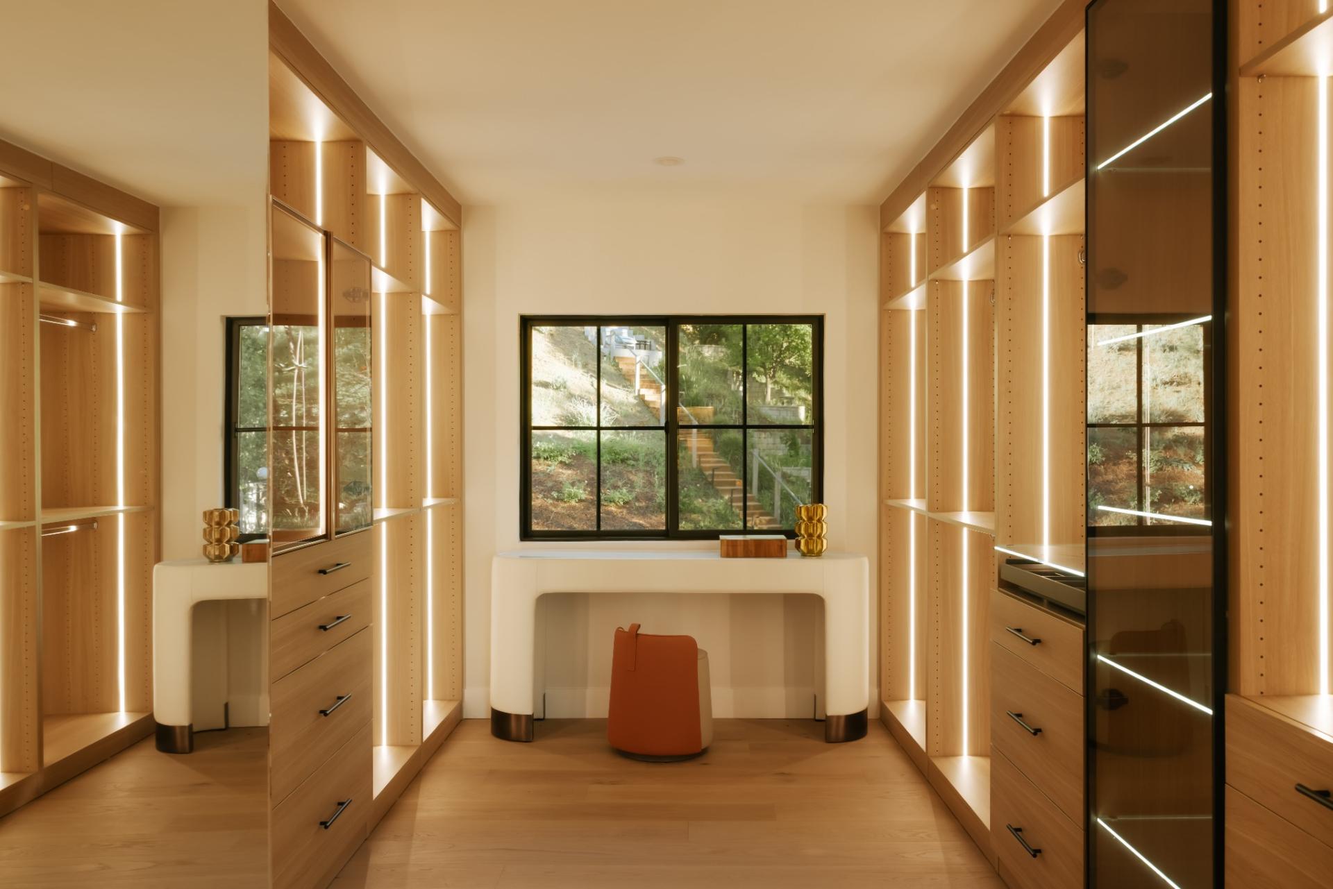 The walk-in closet is built with custom wood cabinetry on both sides, incorporating a mix of drawers, open shelving, and hanging space. 