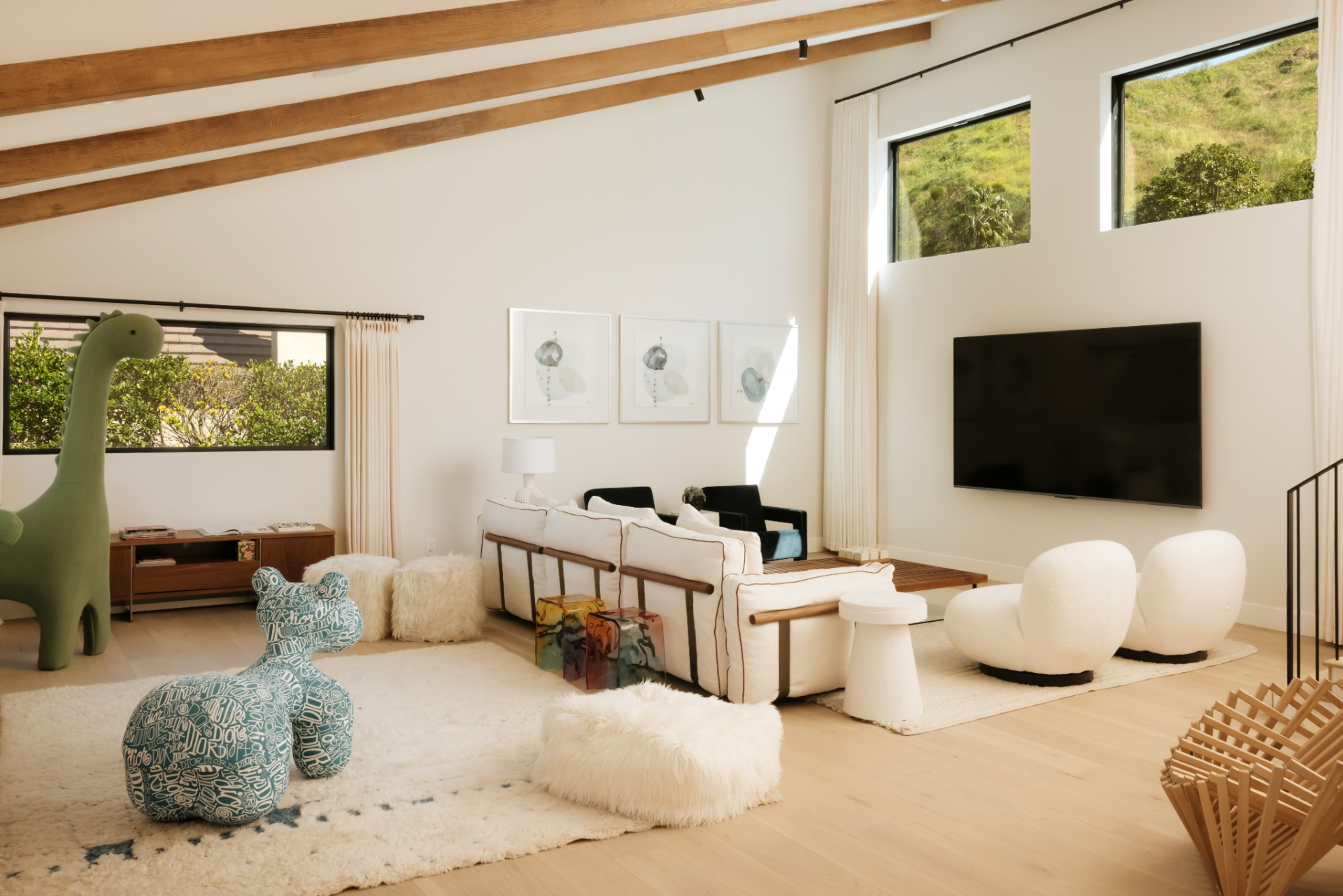 The space is currently arranged as a media lounge and kids' playroom, with a wall-mounted television on one side and an open floor area behind it. 