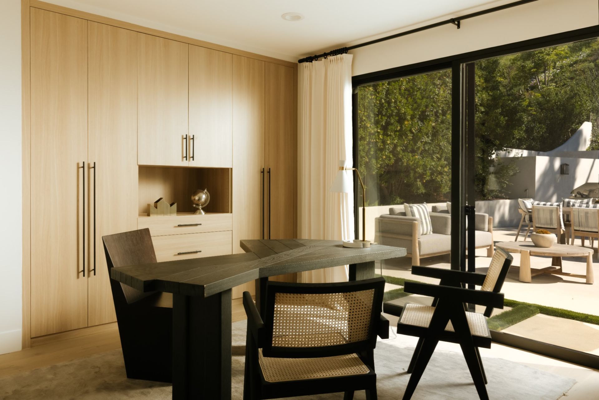 A central desk sits in front of large sliding glass doors, providing direct access to the outdoor patio while filling the room with natural light.