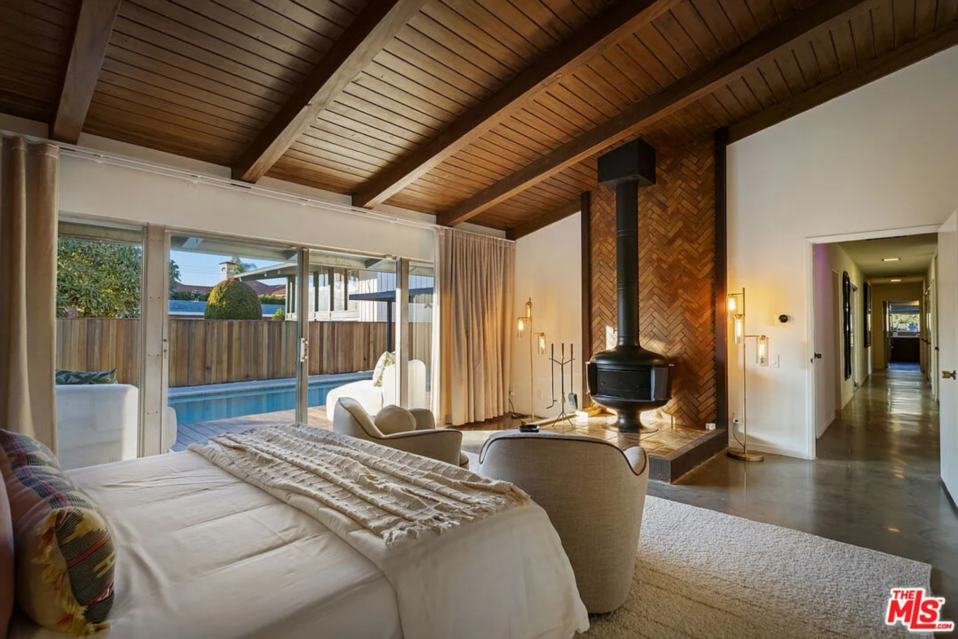 At the center of the room, a suspended fireplace set against a herringbone brick backdrop adds a sculptural focal point.