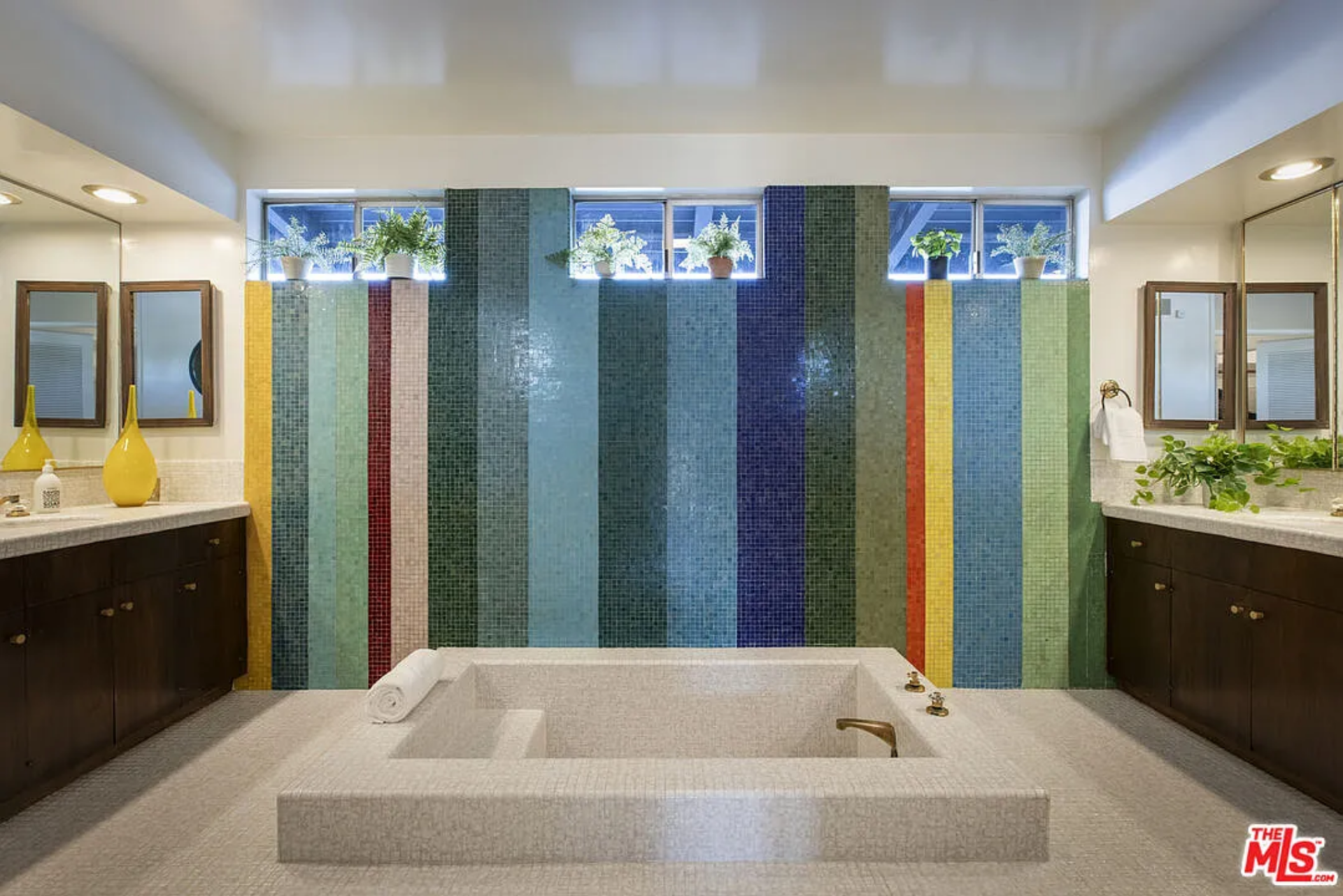 The connected bathroom steals the show with a striking wall of multicolored tilework sitting behind an in-ground bathtub.
